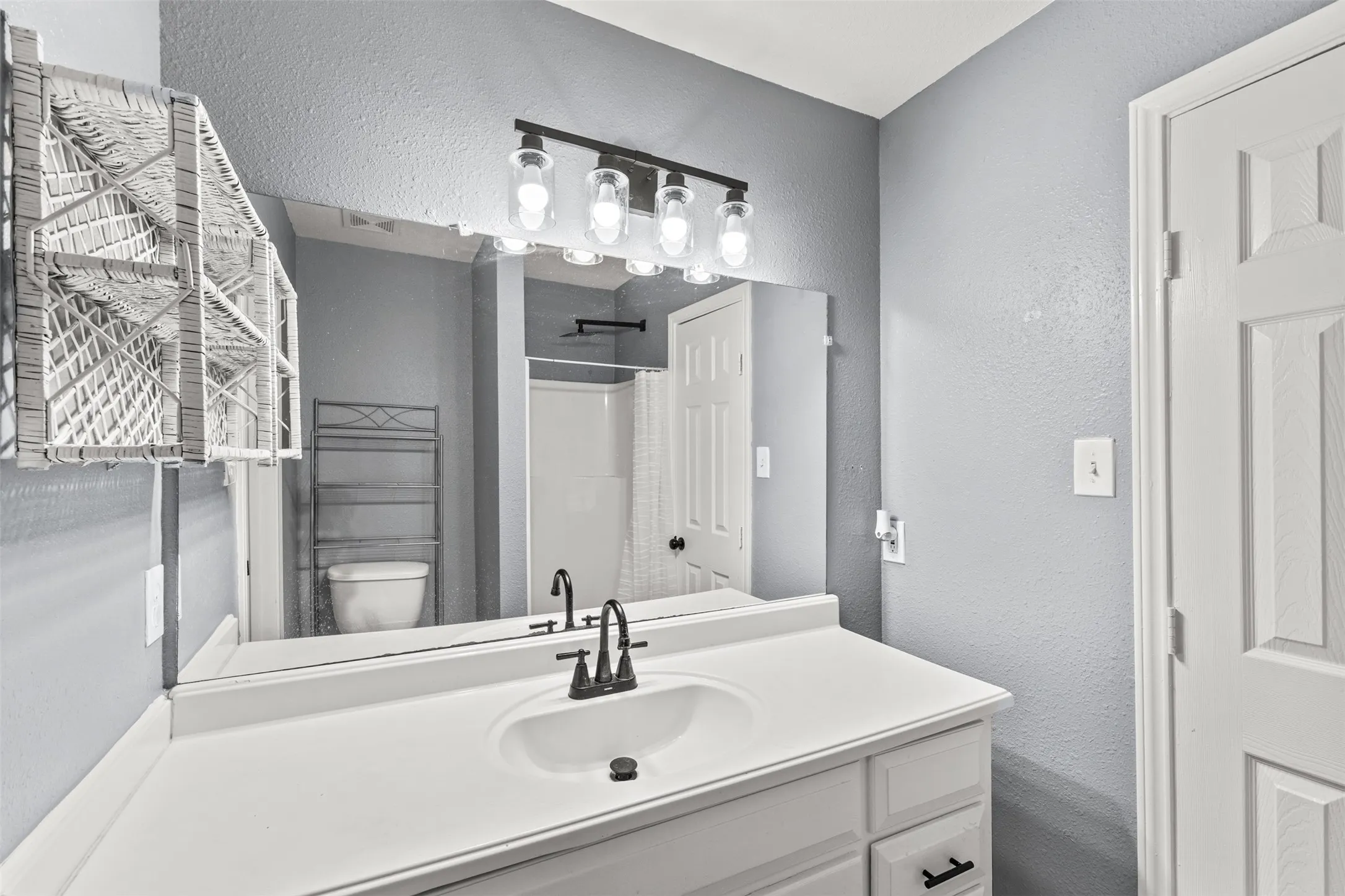 Bathroom vanity with white countertop, integrated sink, and dark bronze faucet hardware