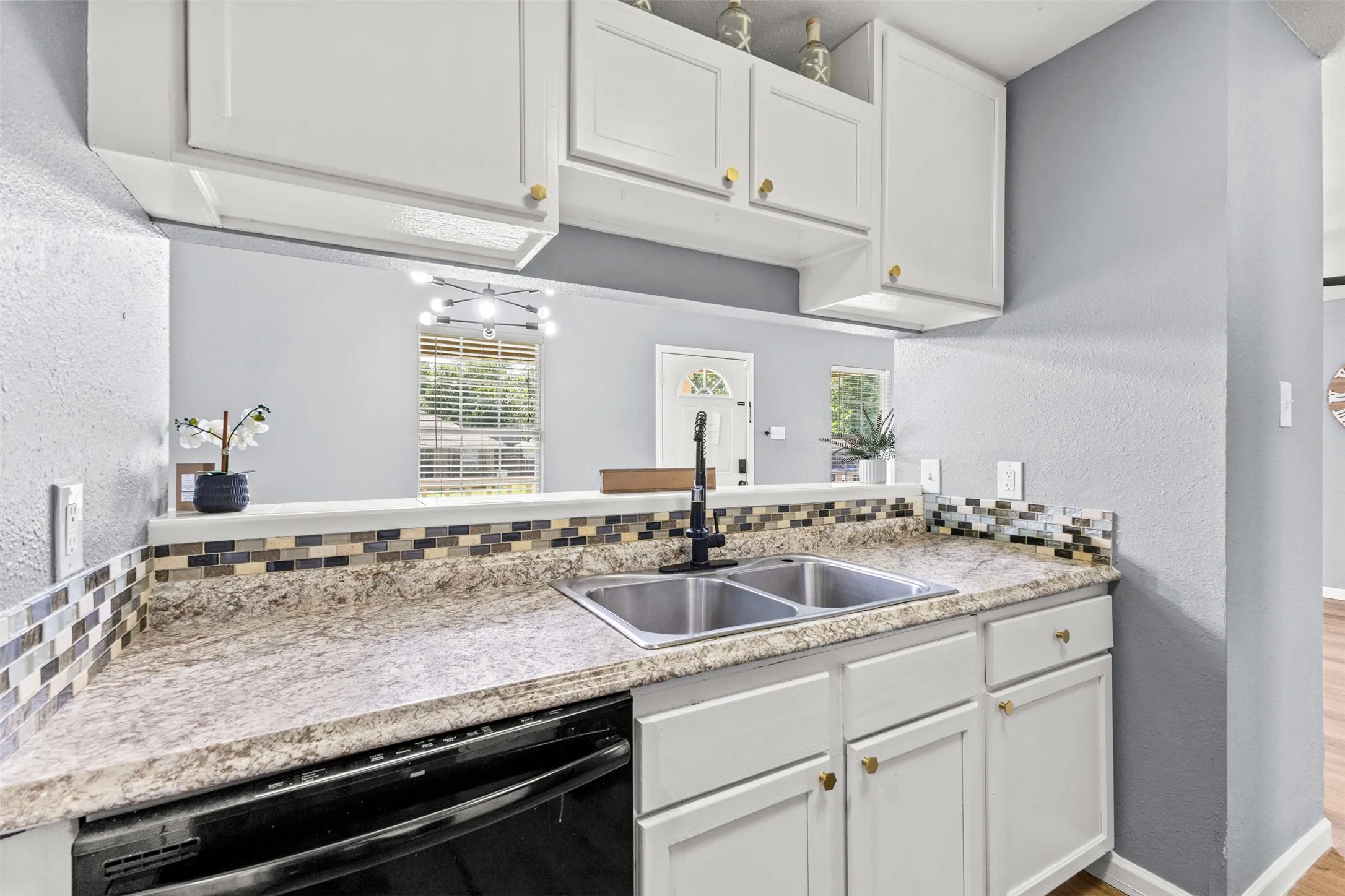 Kitchen featuring a double-basin stainless steel sink with a matte black faucet, granite-look countertops, and a mosaic tile backsplash