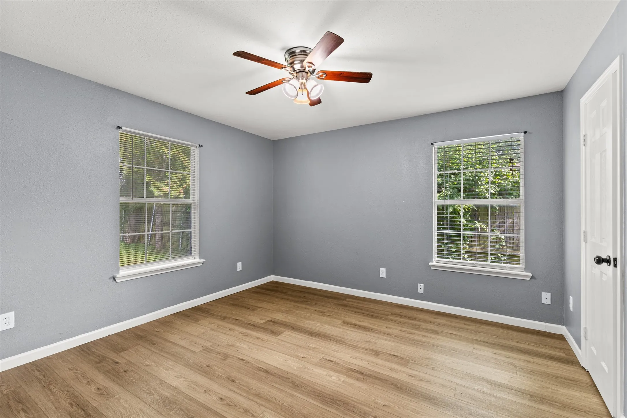 Spacious room featuring wood-finish flooring and two large windows