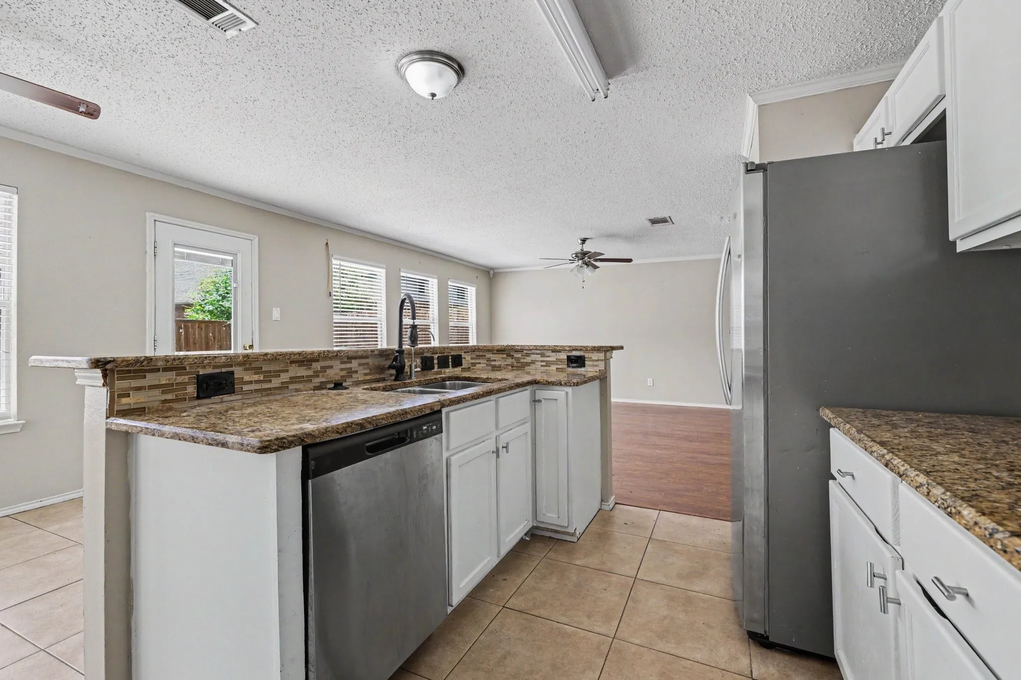 Kitchen featuring granite countertops, a tiled backsplash, and white cabinetry