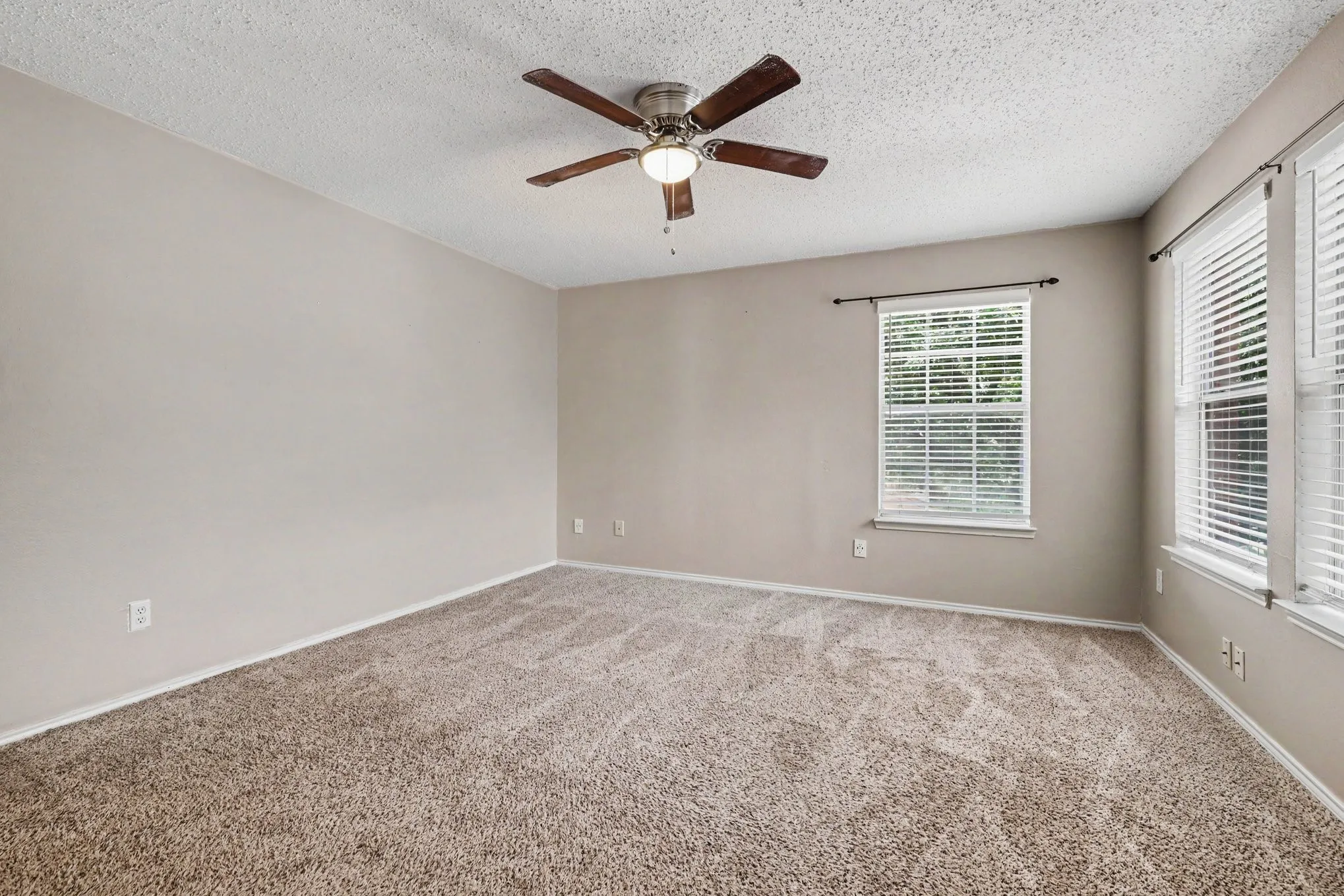 Room featuring light beige walls, two windows with white blinds, and a ceiling fan with integrated lighting