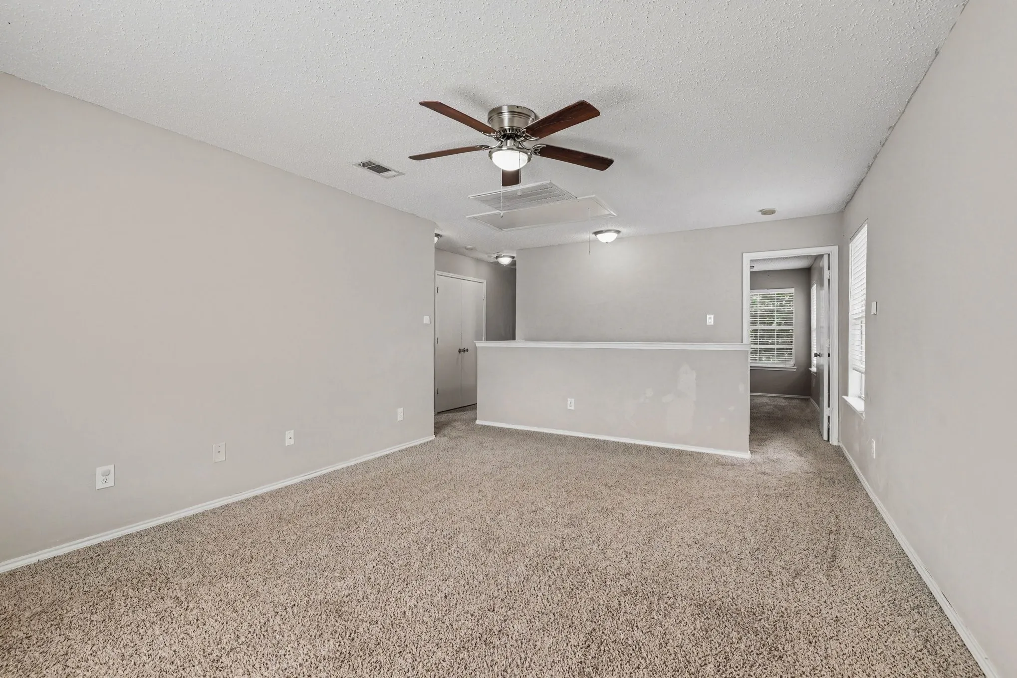 Carpeted living area featuring a ceiling fan with light, recessed lighting, and a half-wall partition