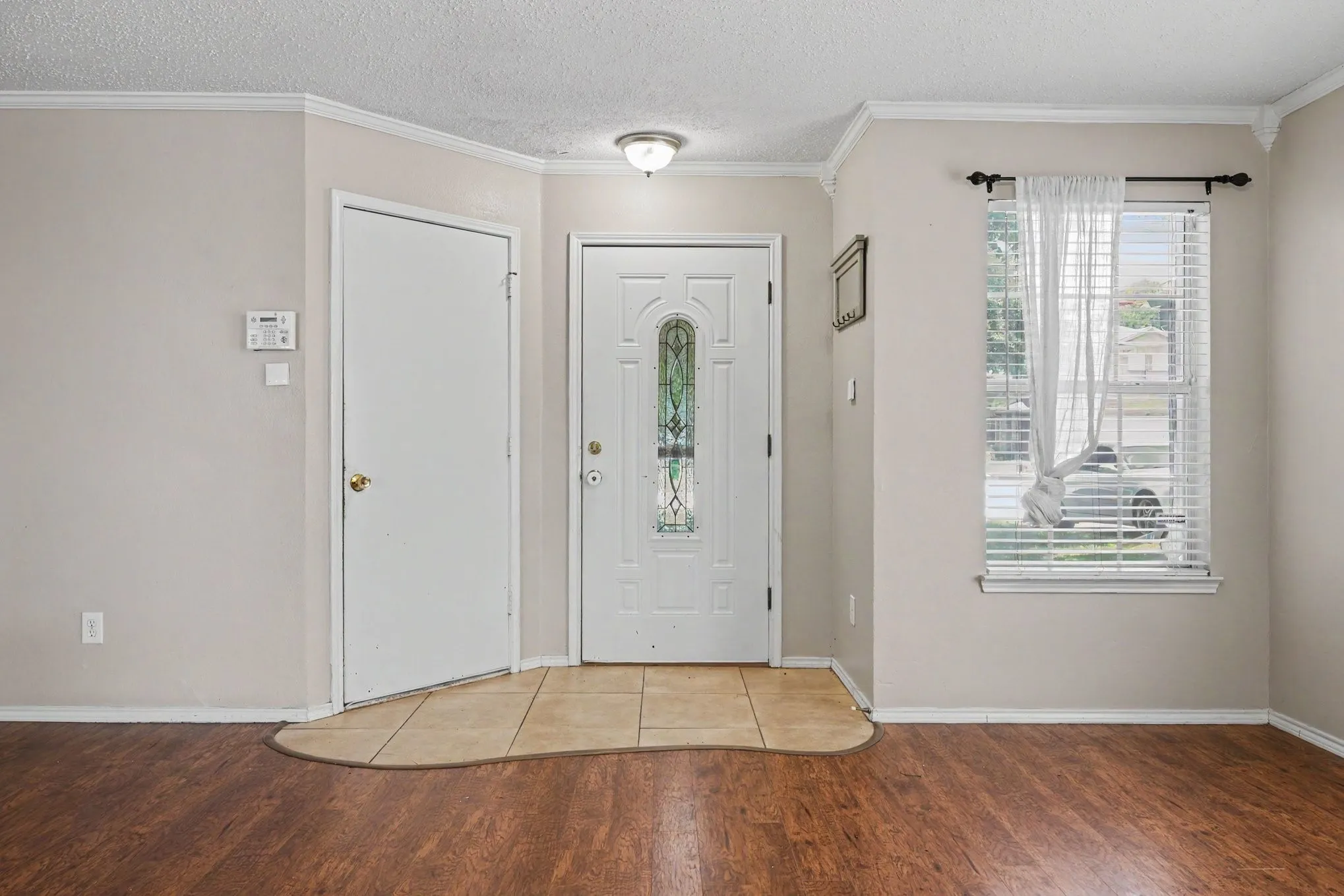 Entryway featuring wood-finish flooring, a white front door with decorative glass, and a tiled landing