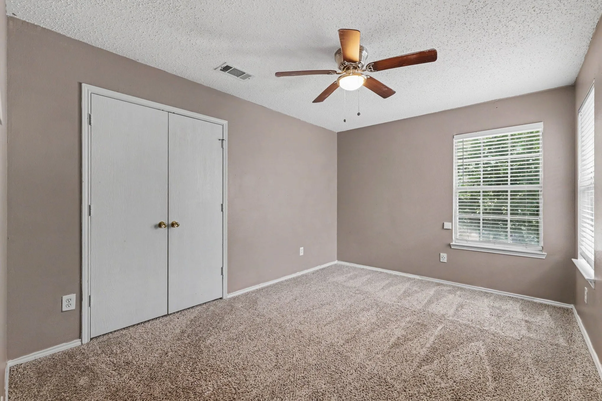 Bedroom featuring neutral wall color, carpet flooring, a window with blinds, a ceiling fan with light fixture, and double-door closet