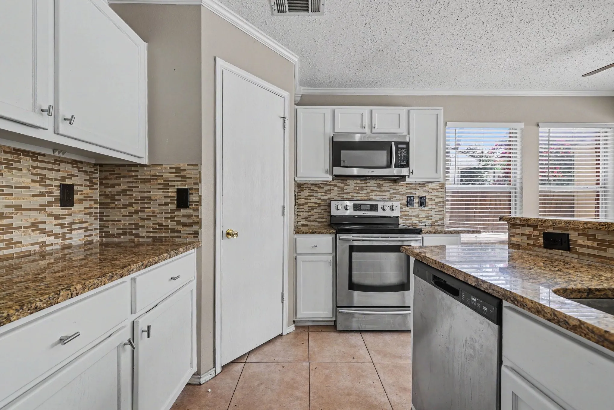 Kitchen featuring white cabinetry, granite-finish countertops, and a mosaic tile backsplash