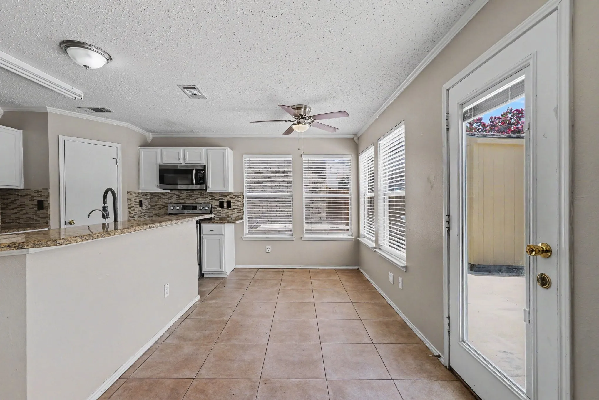 Kitchen with white cabinetry, granite-finish countertops, and a mosaic tile backsplash