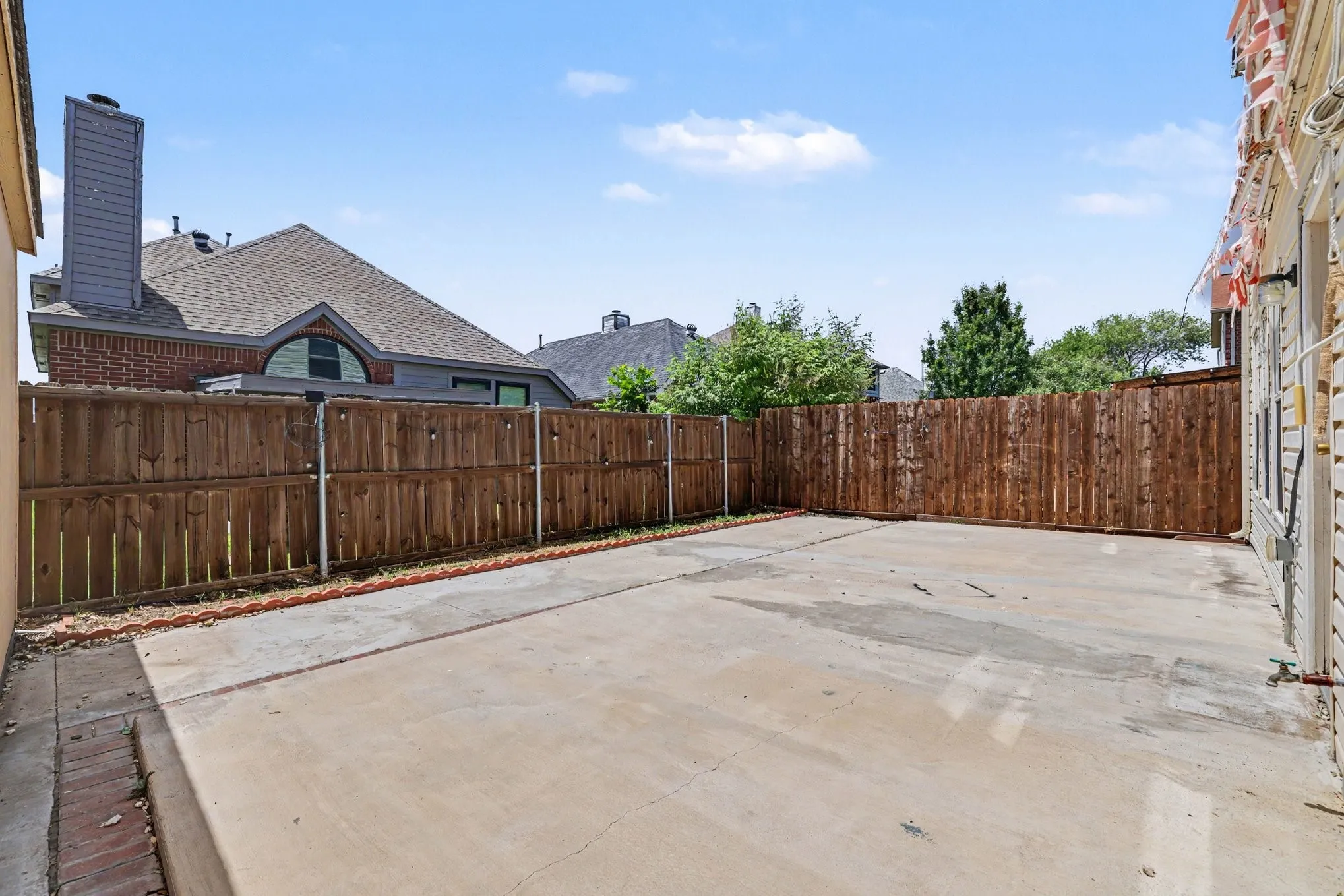 Expansive concrete patio area enclosed by a tall wood fence