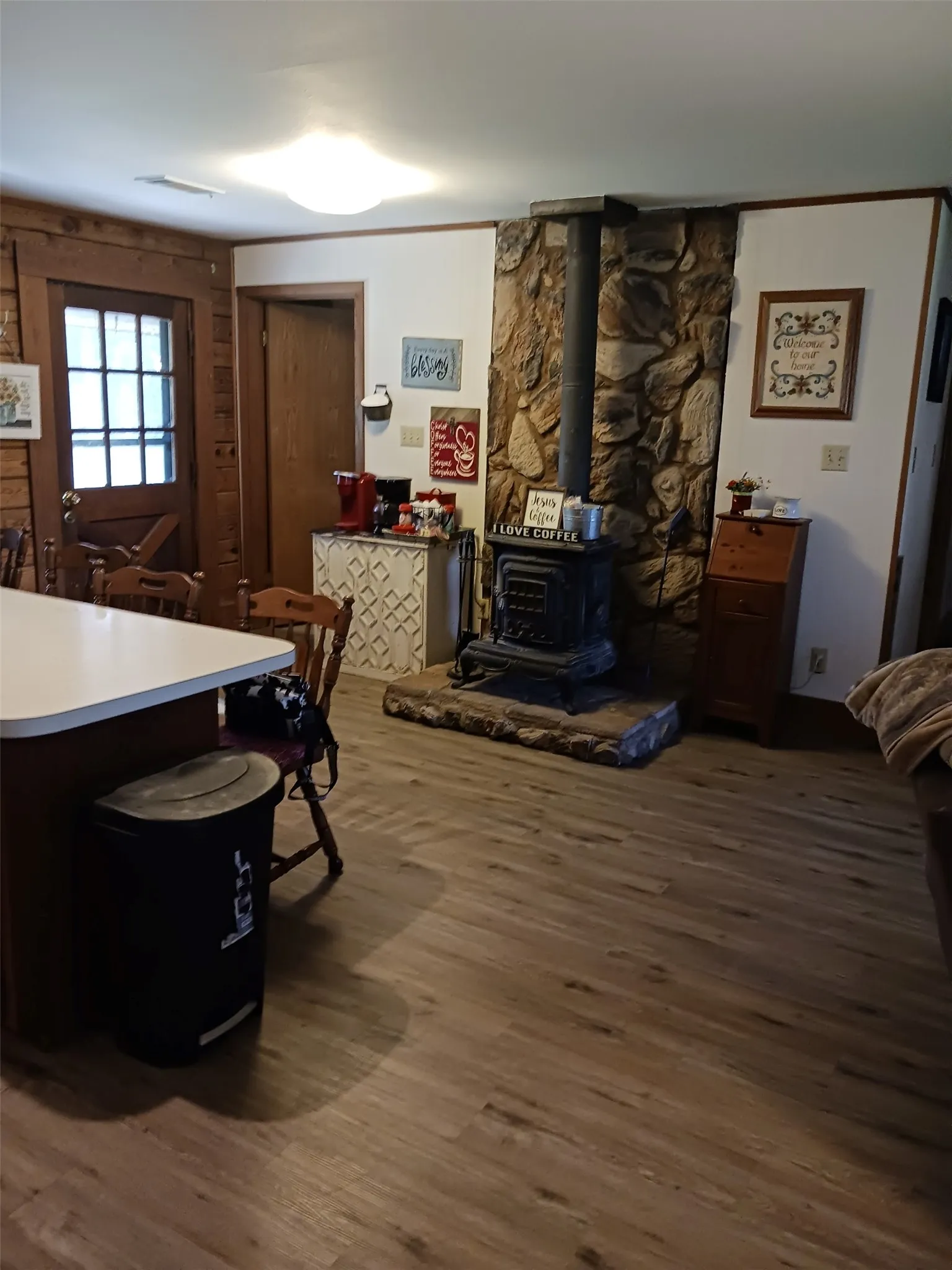 Kitchen featuring wood cabinetry, stainless steel double oven, stainless steel refrigerator, white countertops, and wood-finish flooring