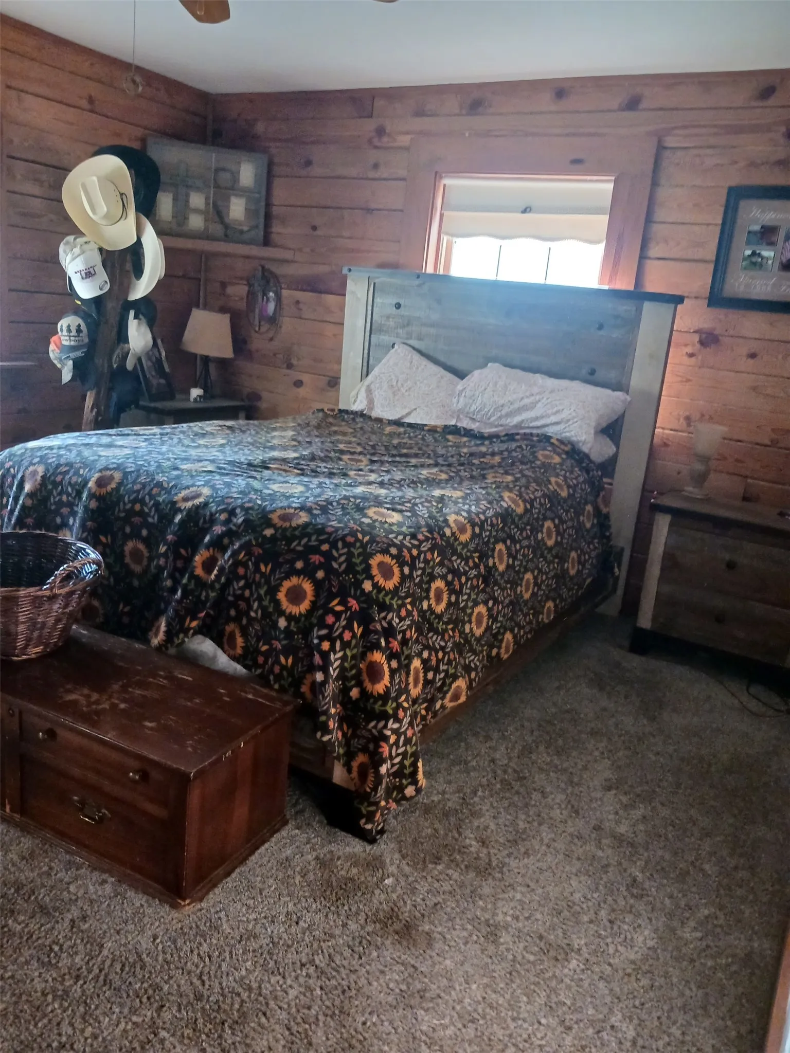 Wood-paneled room featuring a ceiling fan with integrated lighting, twin windows with exterior views, and a solid wood door