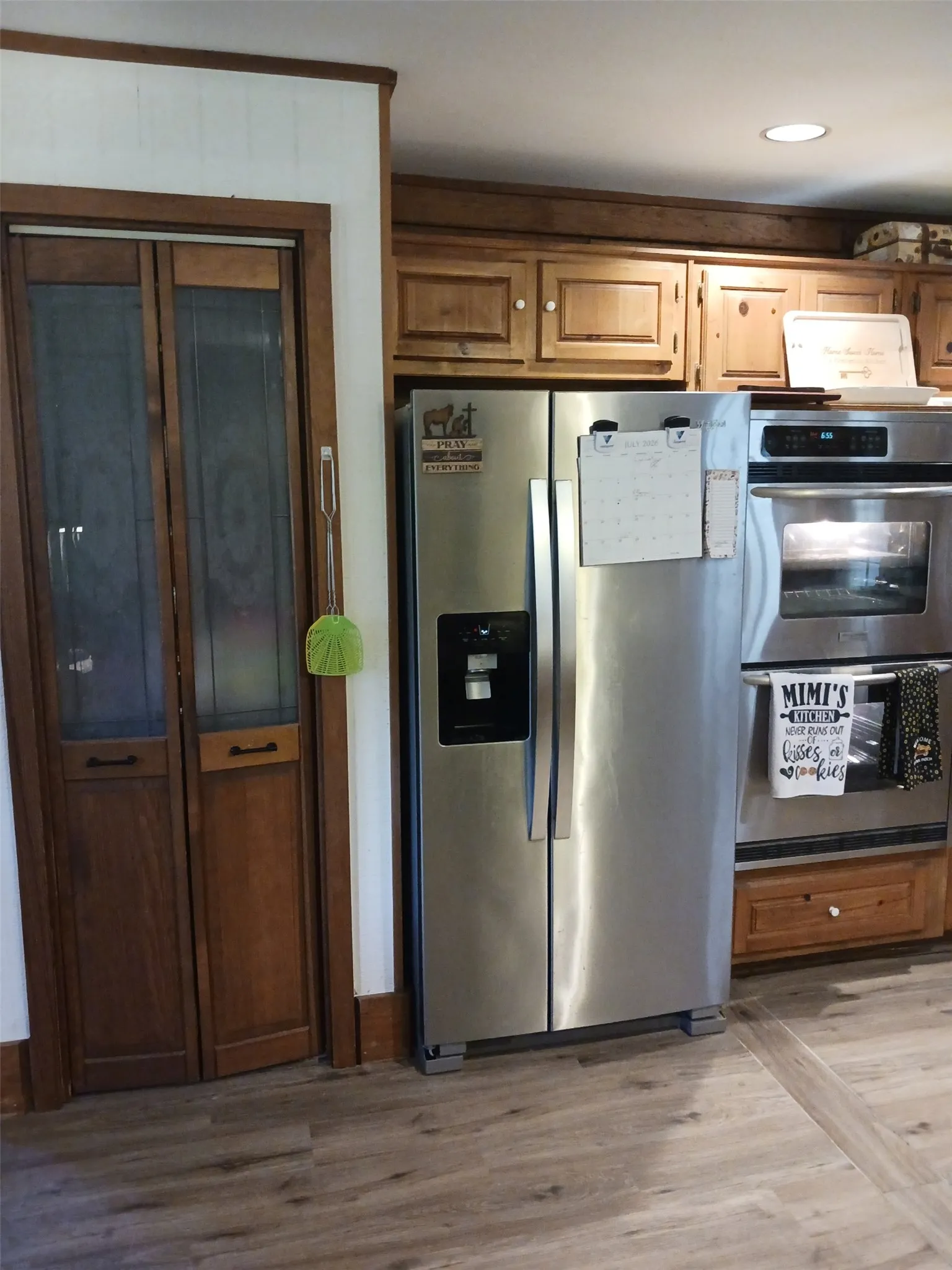 Open-concept kitchen featuring wood-finish flooring, a central island with white countertop, stainless steel appliances, and wood paneling throughout