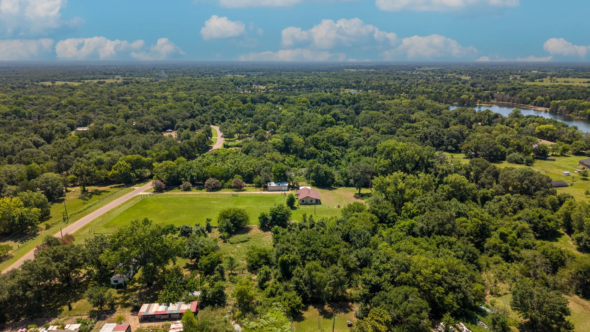 Expansive land parcel featuring dense tree coverage, a cleared grass area, and a visible road