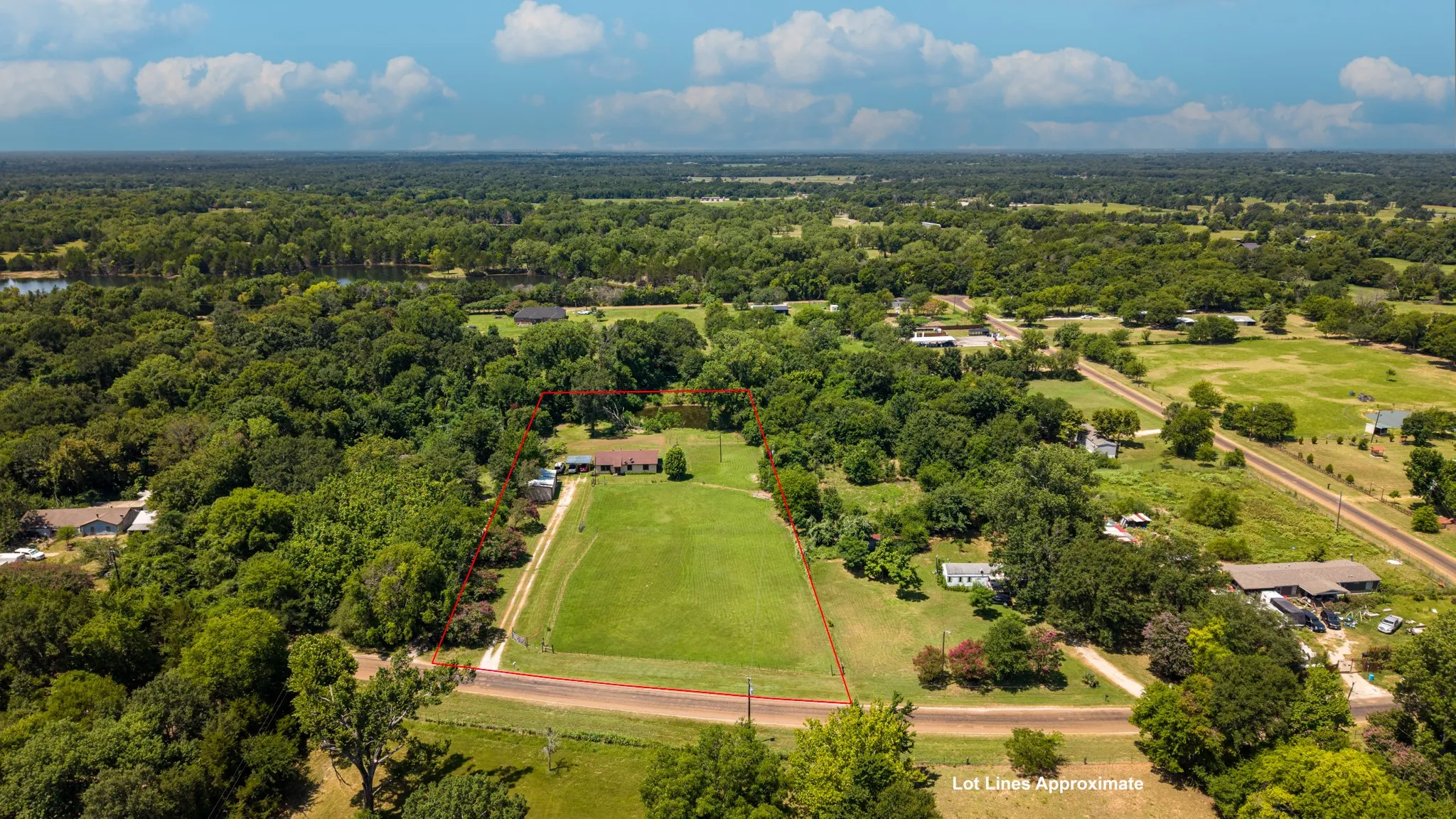 Expansive aerial view showcasing a large parcel of land with extensive wooded areas and open grassy fields