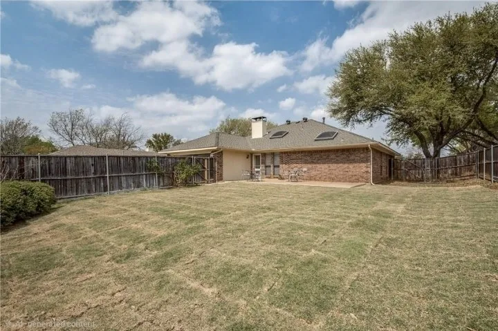 Expansive backyard featuring a brick exterior, a patio area, a wood fence, and mature trees