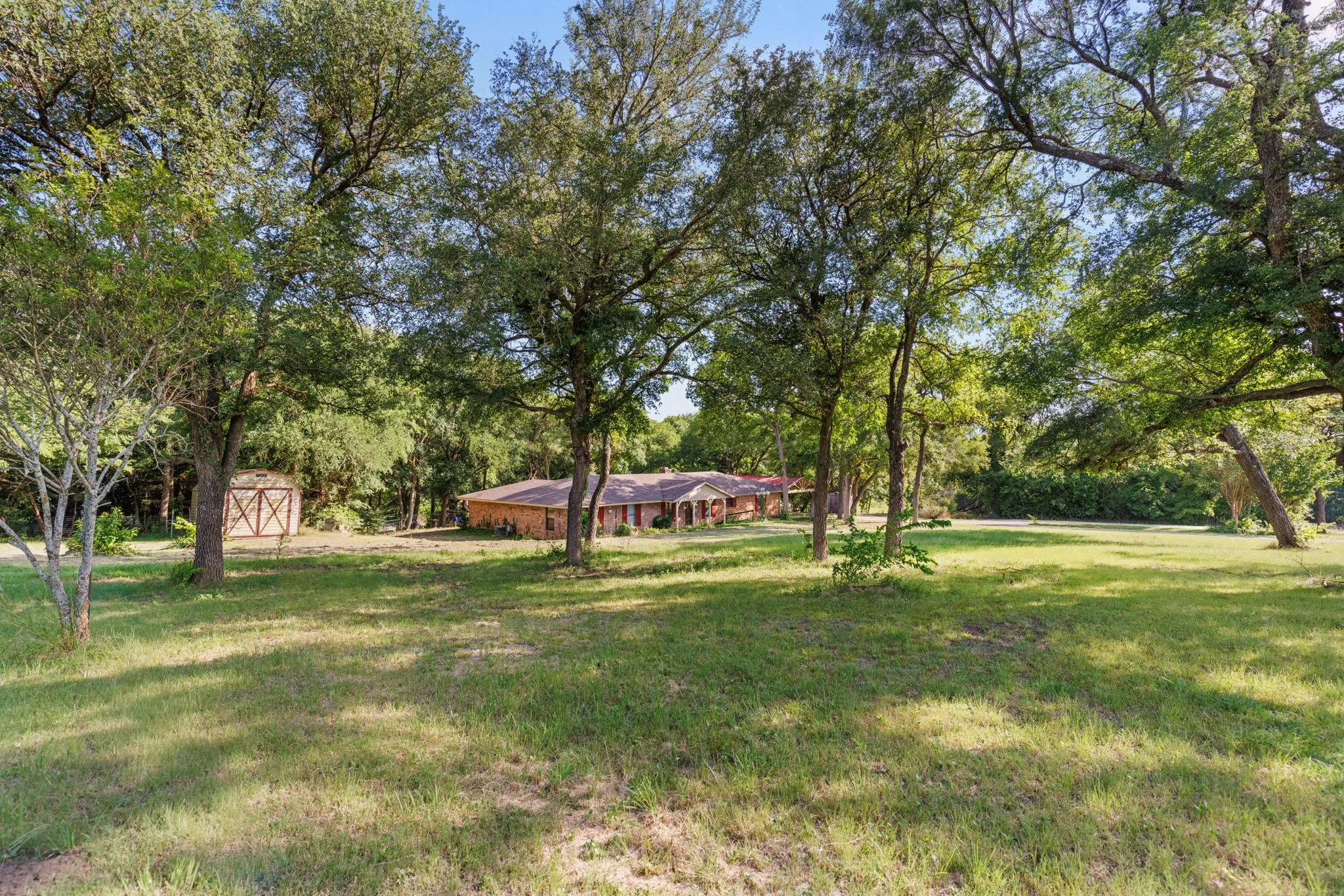 Expansive grassy lot featuring mature trees providing ample shade