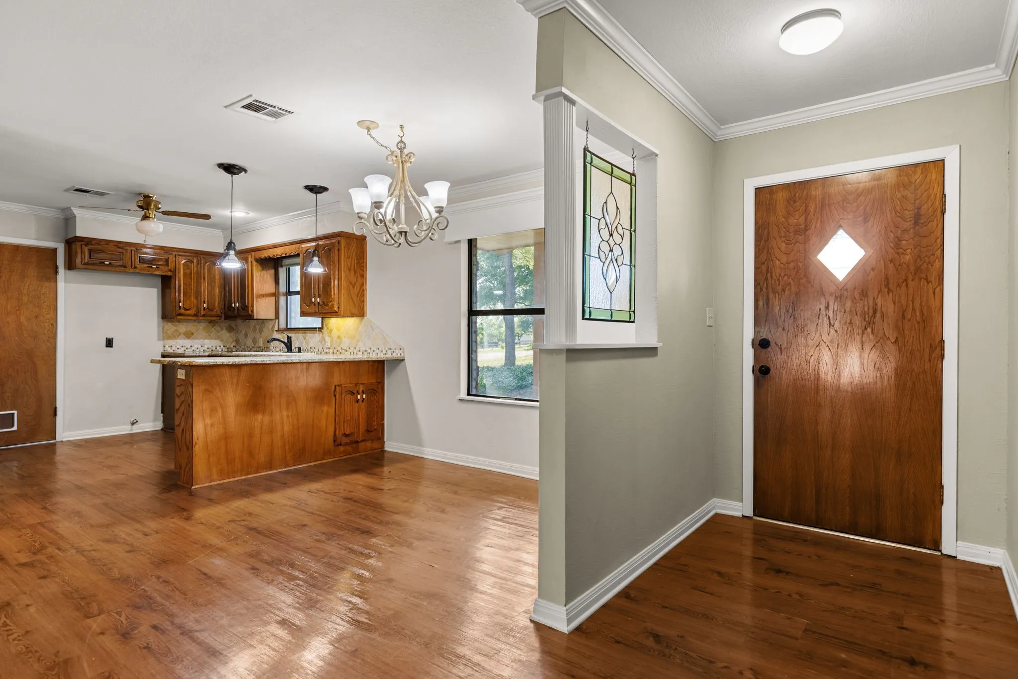 Entryway with a wood-finish door featuring a diamond-shaped glass insert, accompanied by a stained-glass window panel