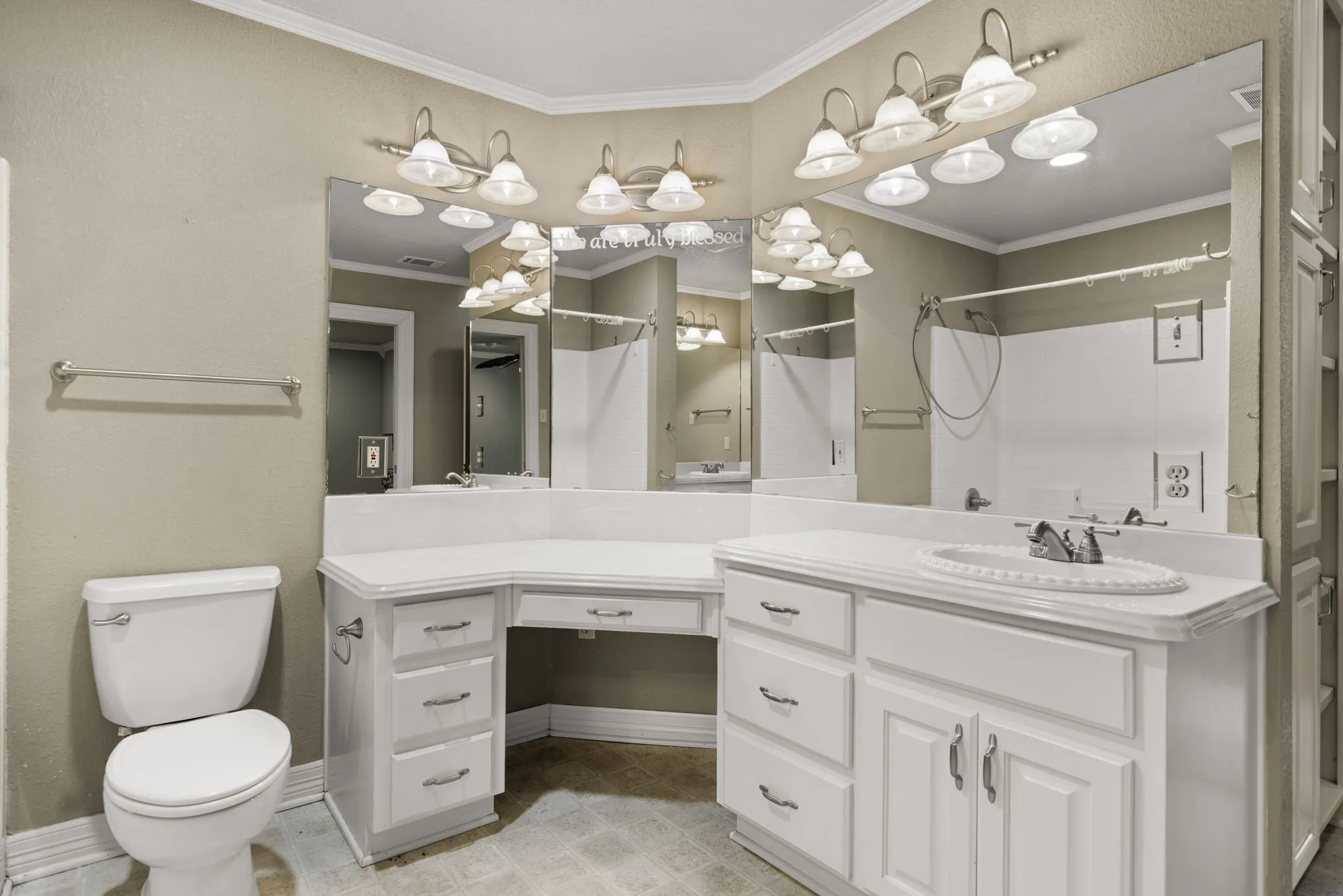 Bathroom featuring a double vanity, makeup desk, extensive mirror, and overhead lighting