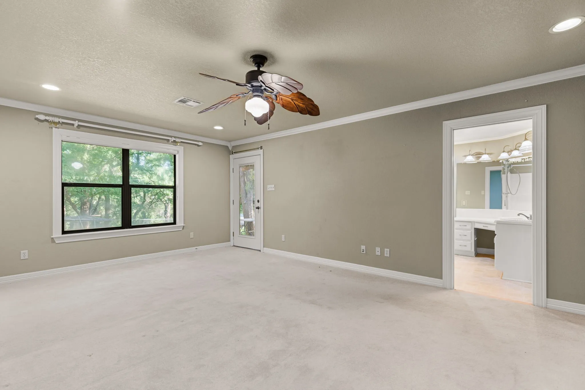 Spacious room featuring neutral carpeting, a large window, a glass-paned door, a ceiling fan, and recessed lighting