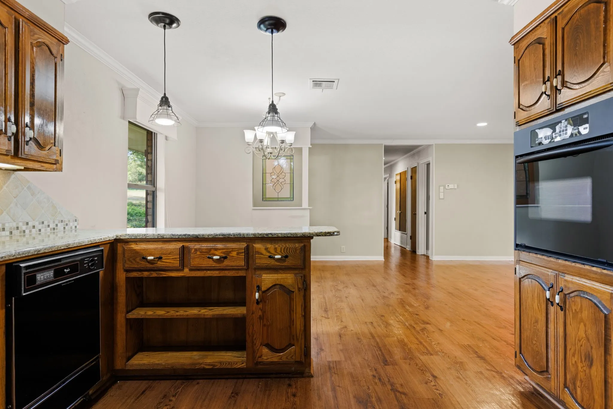 Kitchen featuring warm-toned wood cabinetry, granite-finish countertops, and a tiled backsplash