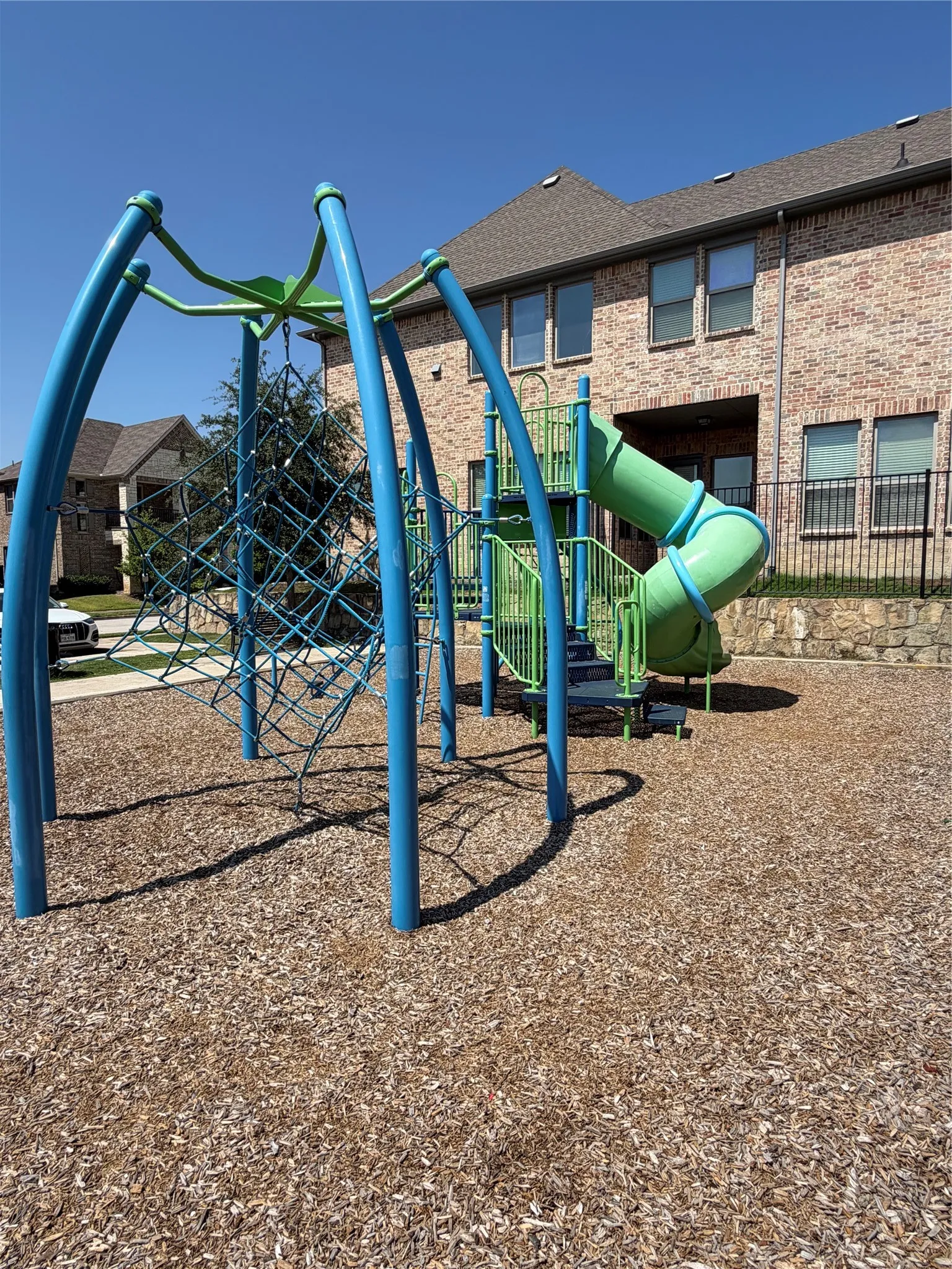 Community playground featuring a climbing structure with a net and a spiral slide