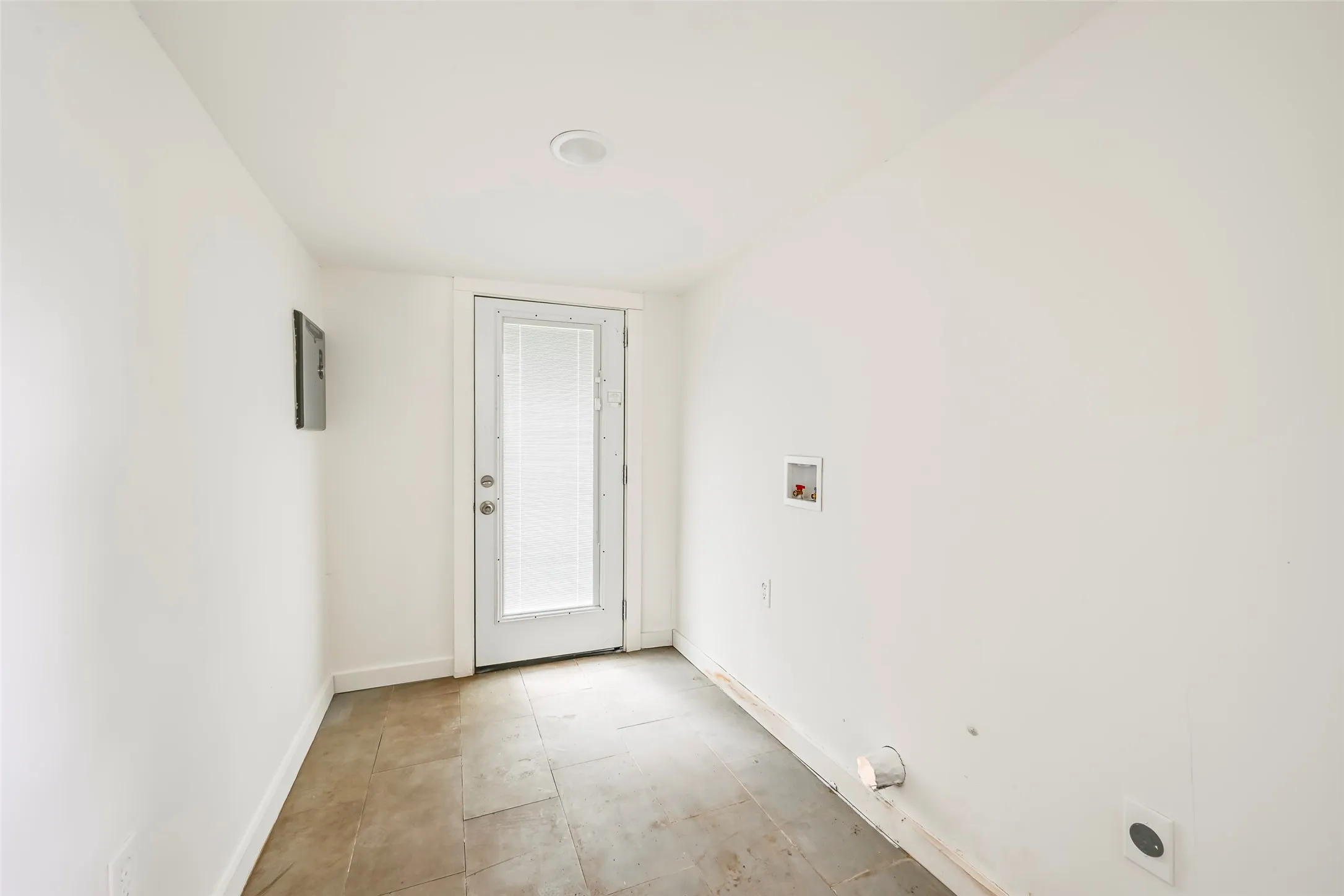 Utility area featuring a glass-paneled door, tiled flooring, overhead lighting, and dedicated hookups