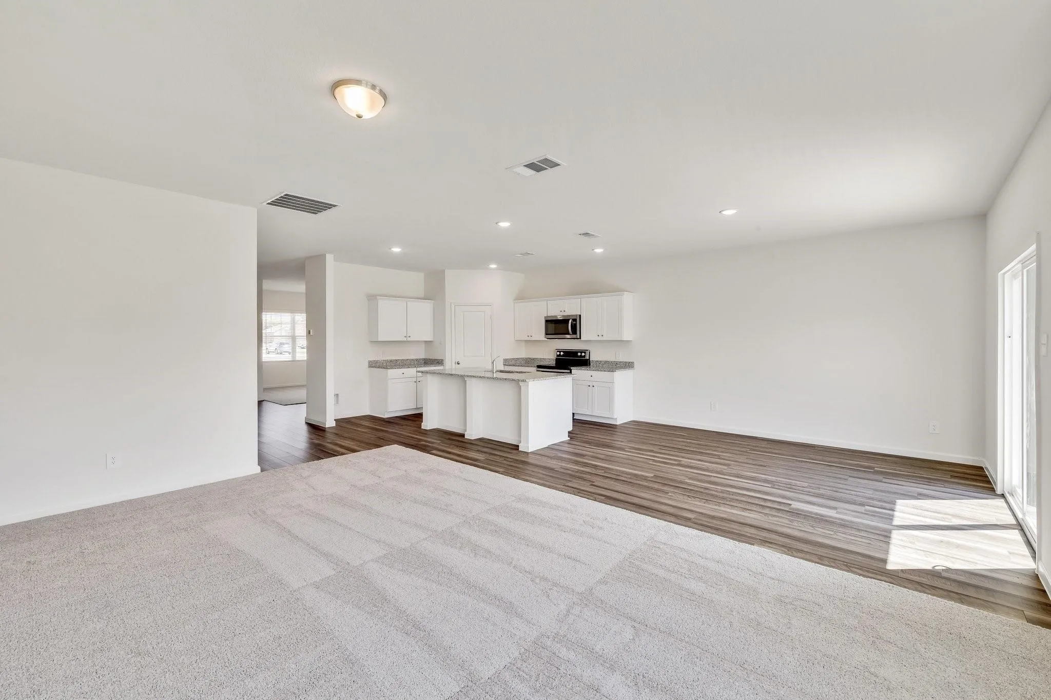 Spacious open-concept living area featuring a kitchen with white cabinetry and an island