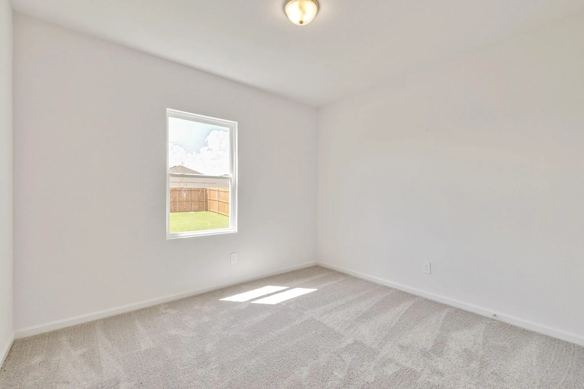 Bright interior room featuring a single window, neutral wall paint, and light gray carpet flooring