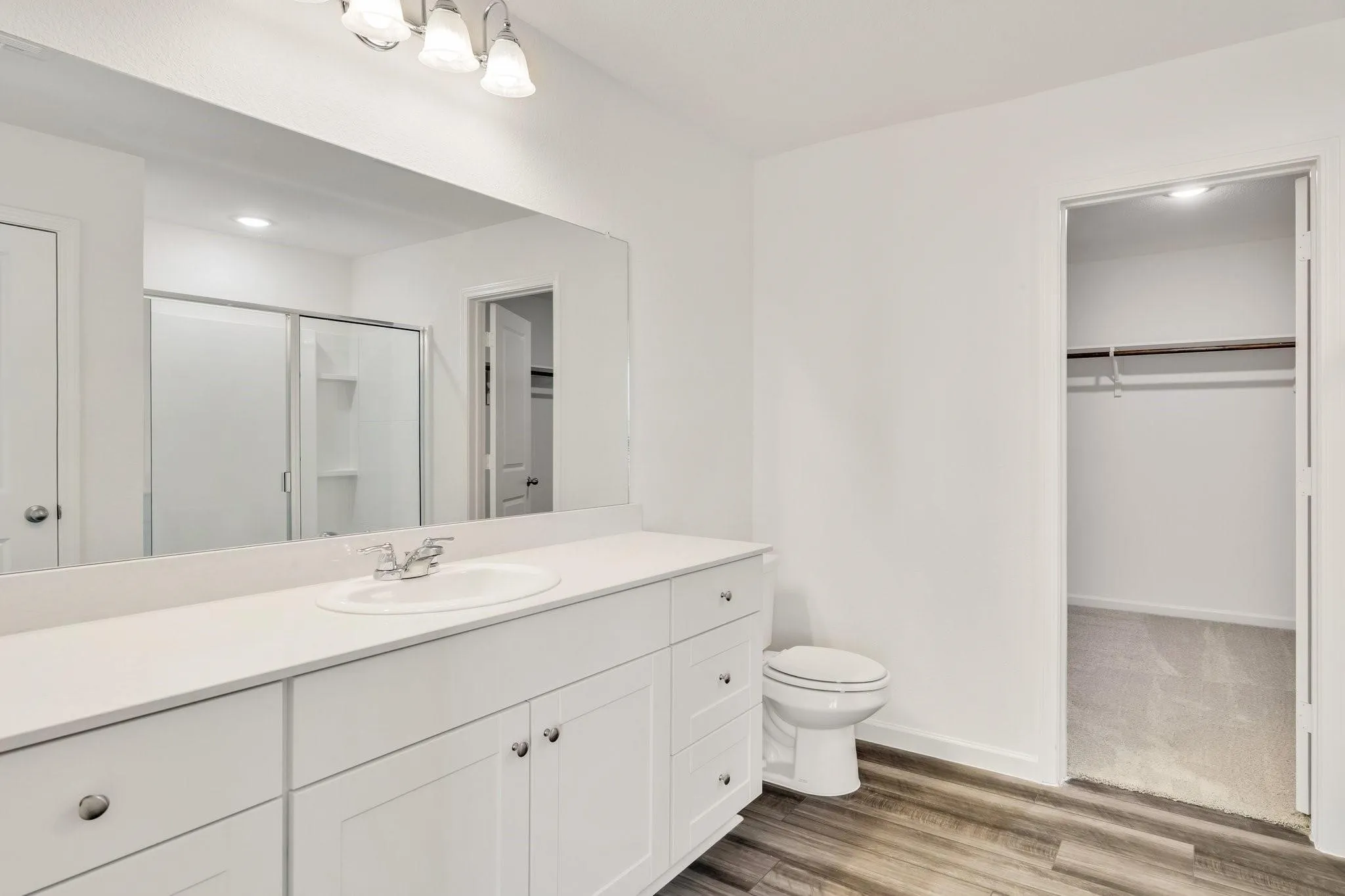 Bathroom featuring a white vanity with integrated sink, chrome faucet, and expansive mirror