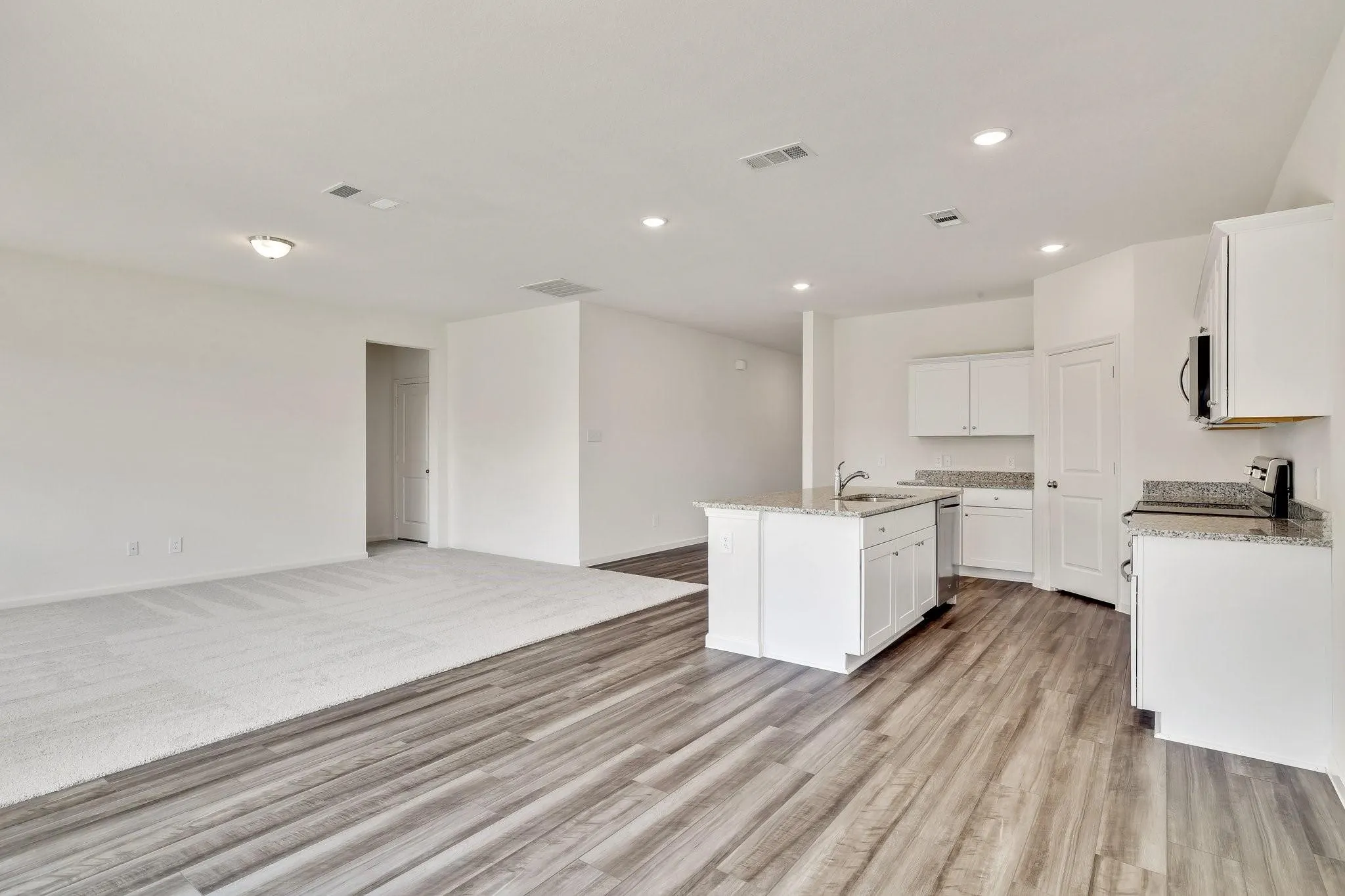 Kitchen featuring white cabinetry, granite countertops, and a central island with a stainless steel sink
