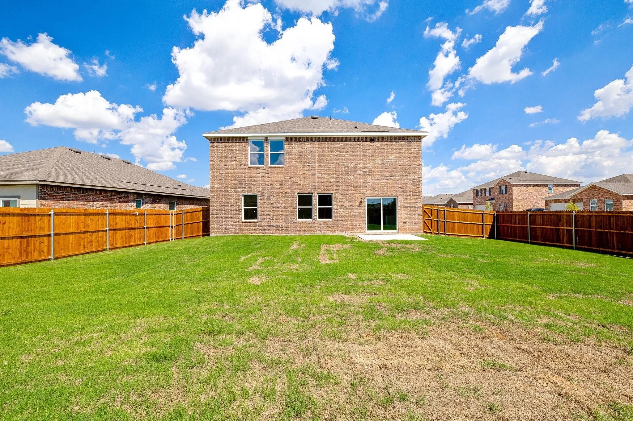 Expansive backyard featuring a manicured lawn, full perimeter wood fencing, and a concrete patio