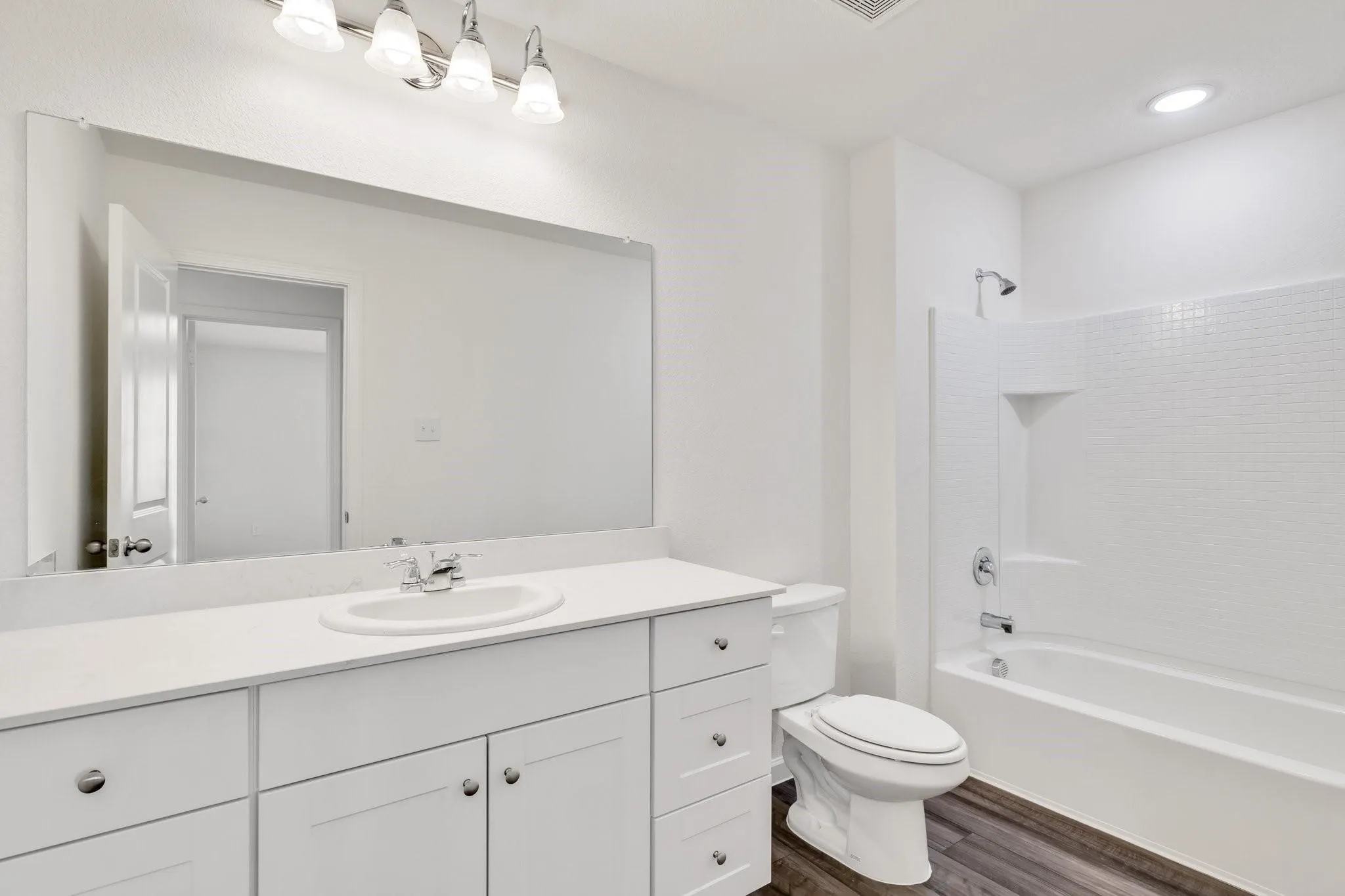 Bathroom featuring a white vanity with integrated sink, white countertop, and expansive wall mirror
