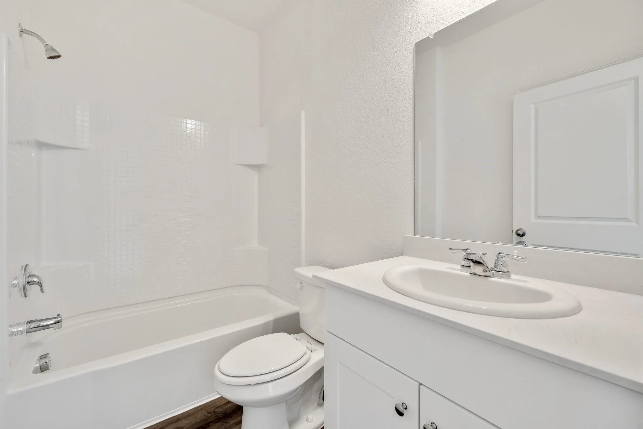 Bathroom featuring a white vanity with an integrated sink, chrome faucet, and a large wall-mounted mirror