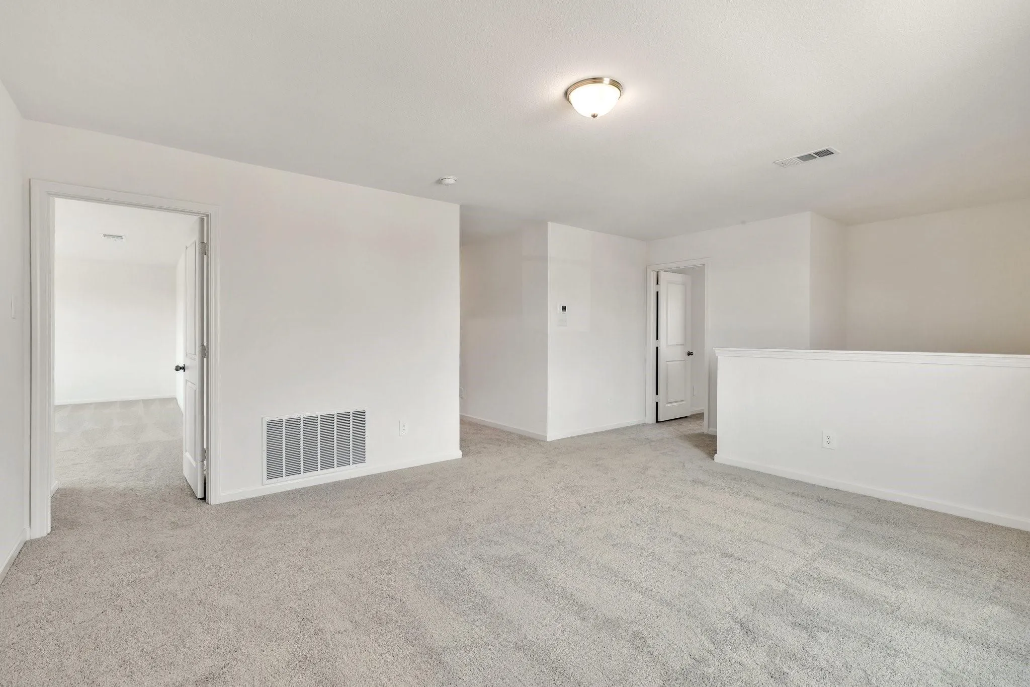 Upper-level interior space featuring light gray carpeting and white painted walls