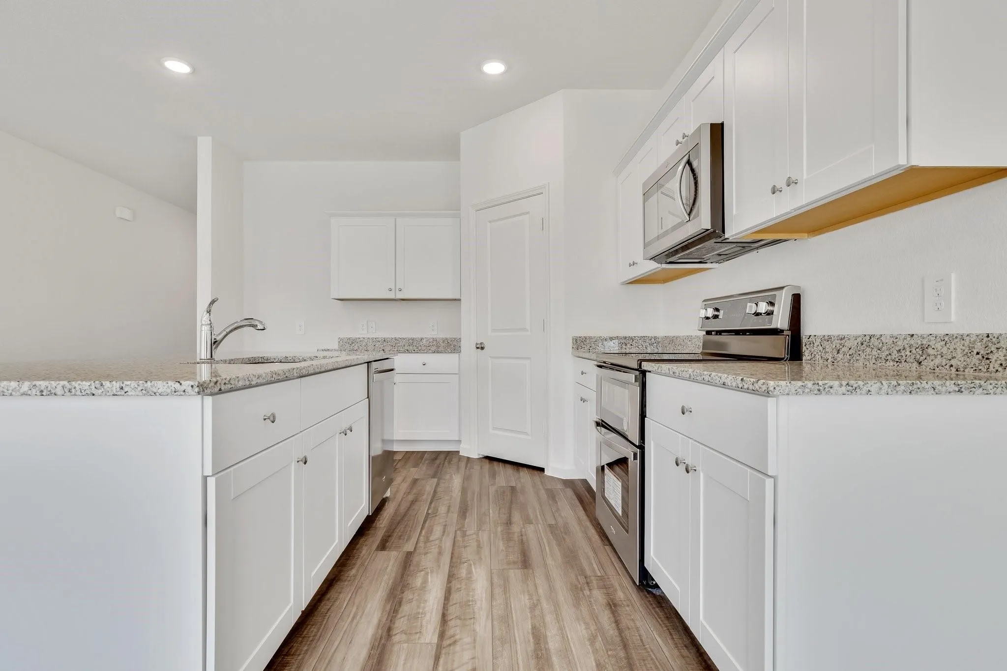 Modern kitchen featuring white cabinetry and light-toned granite-style countertops