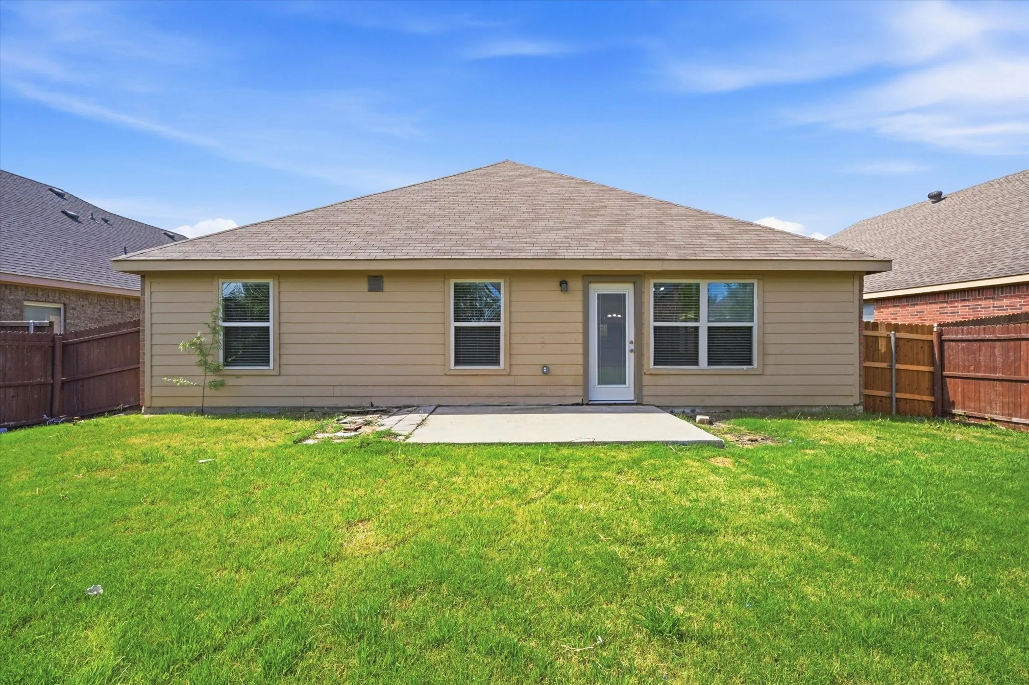 Expansive backyard featuring a manicured lawn, a concrete patio, and a privacy fence