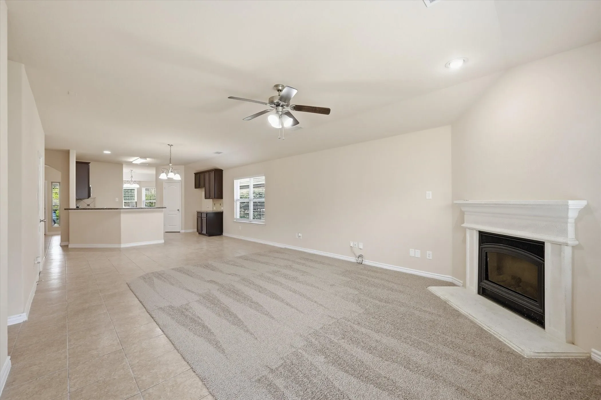 Spacious interior featuring a white mantle fireplace, ceiling fan, and recessed lighting