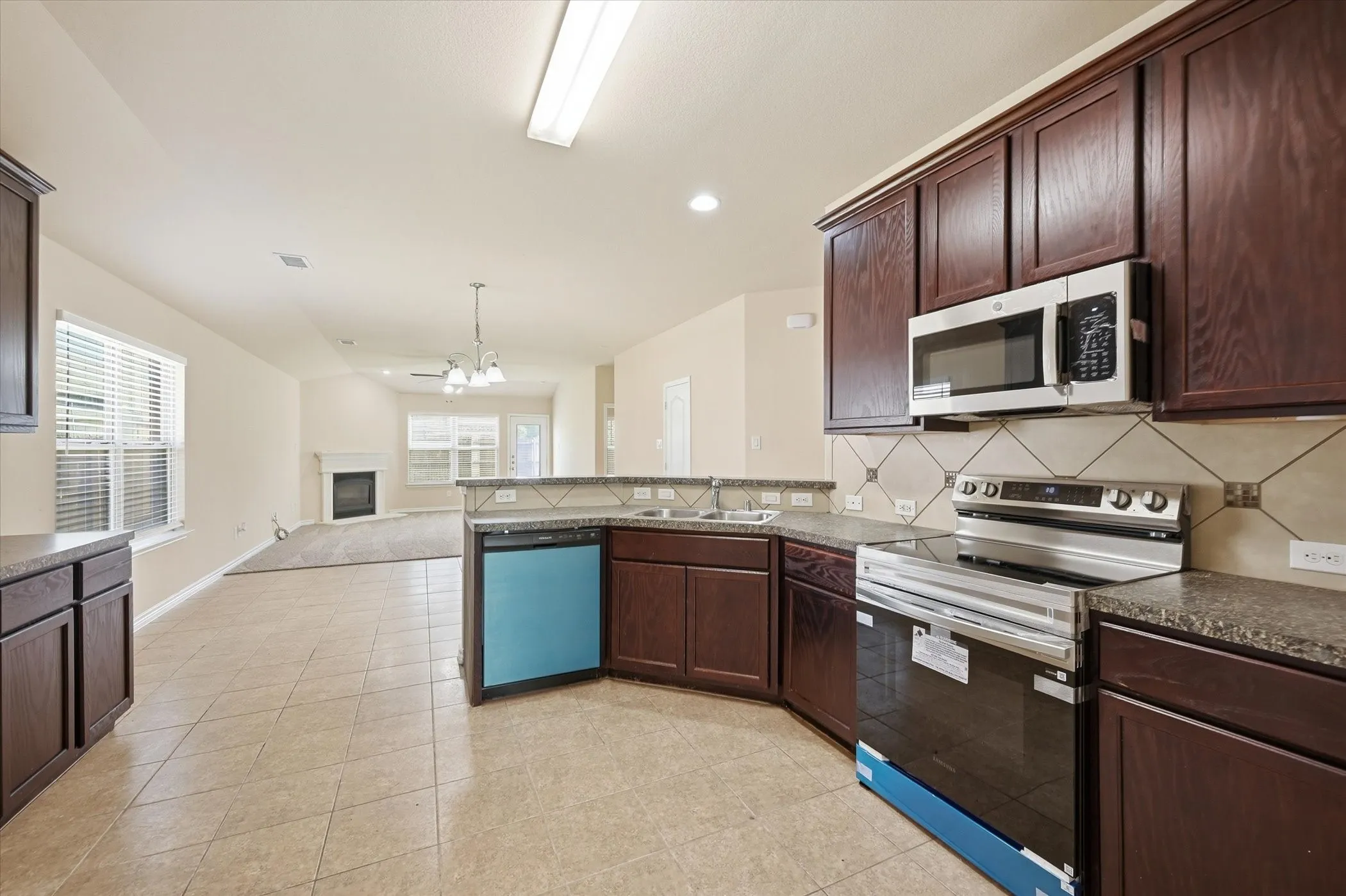 Kitchen featuring tile flooring, dark wood-finish cabinetry, stone-finish countertops, and a tile backsplash
