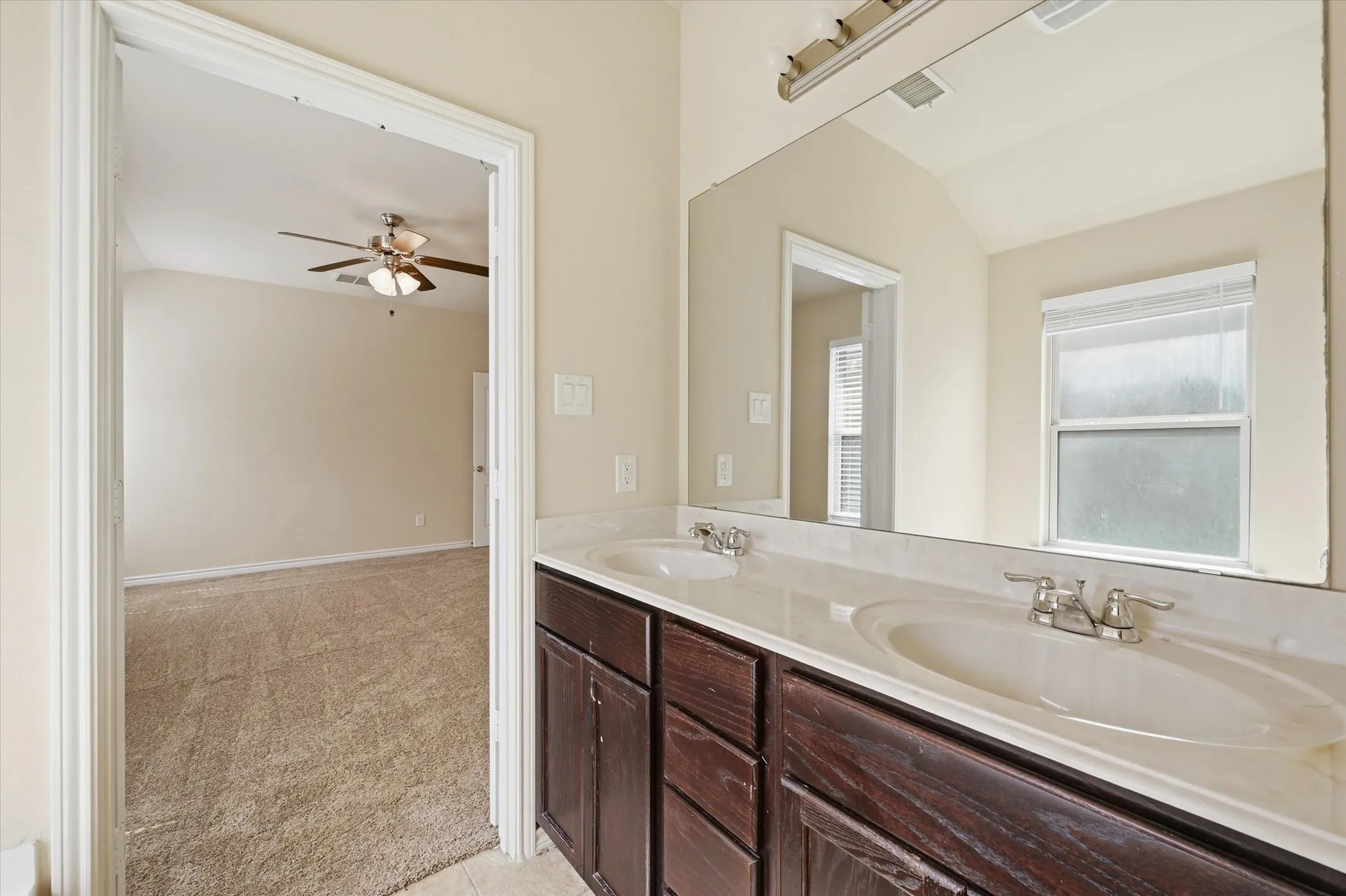 Double vanity featuring integrated sinks, chrome faucets, and dark wood cabinetry