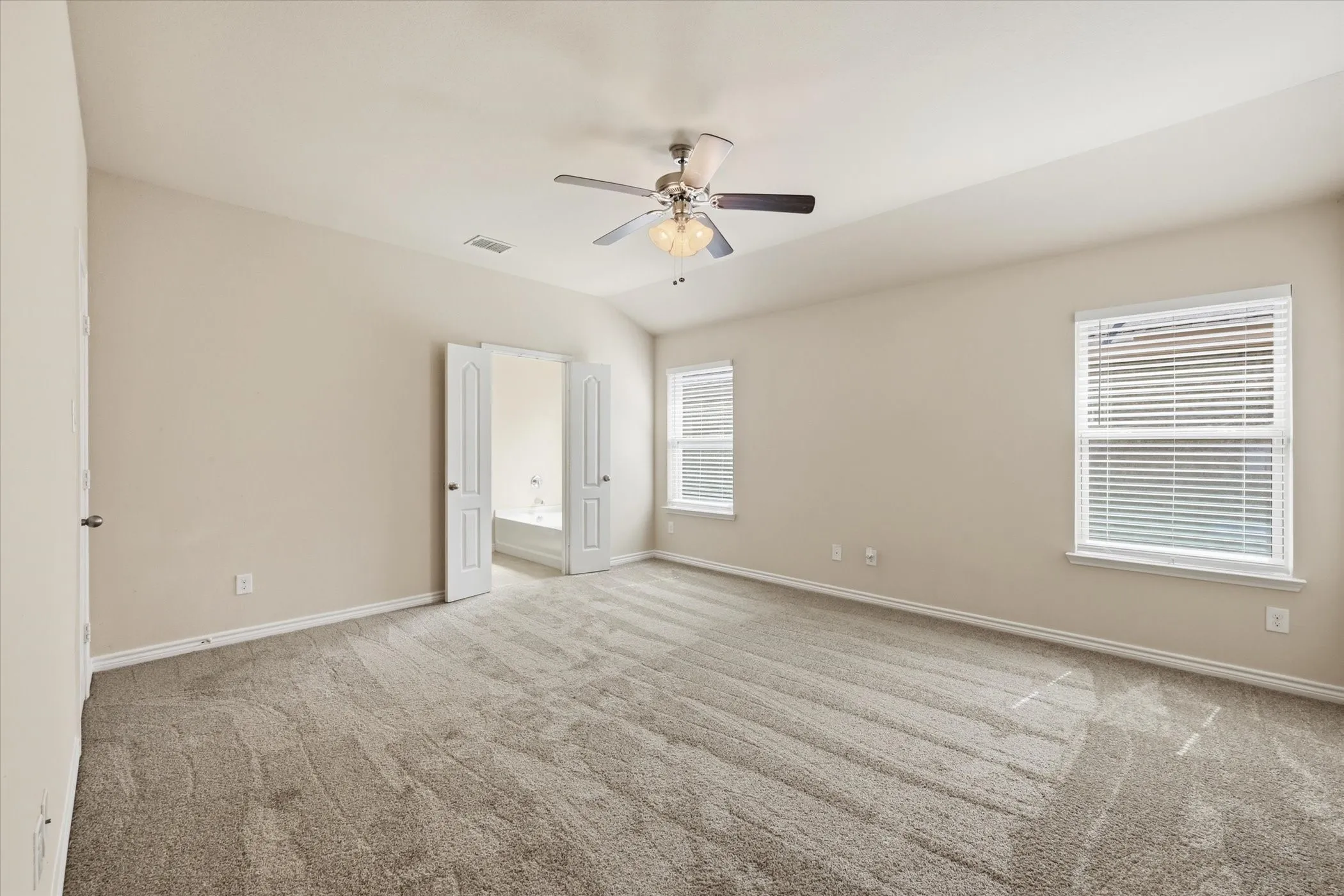 Spacious room featuring vaulted ceilings, light-toned walls, and plush carpeting