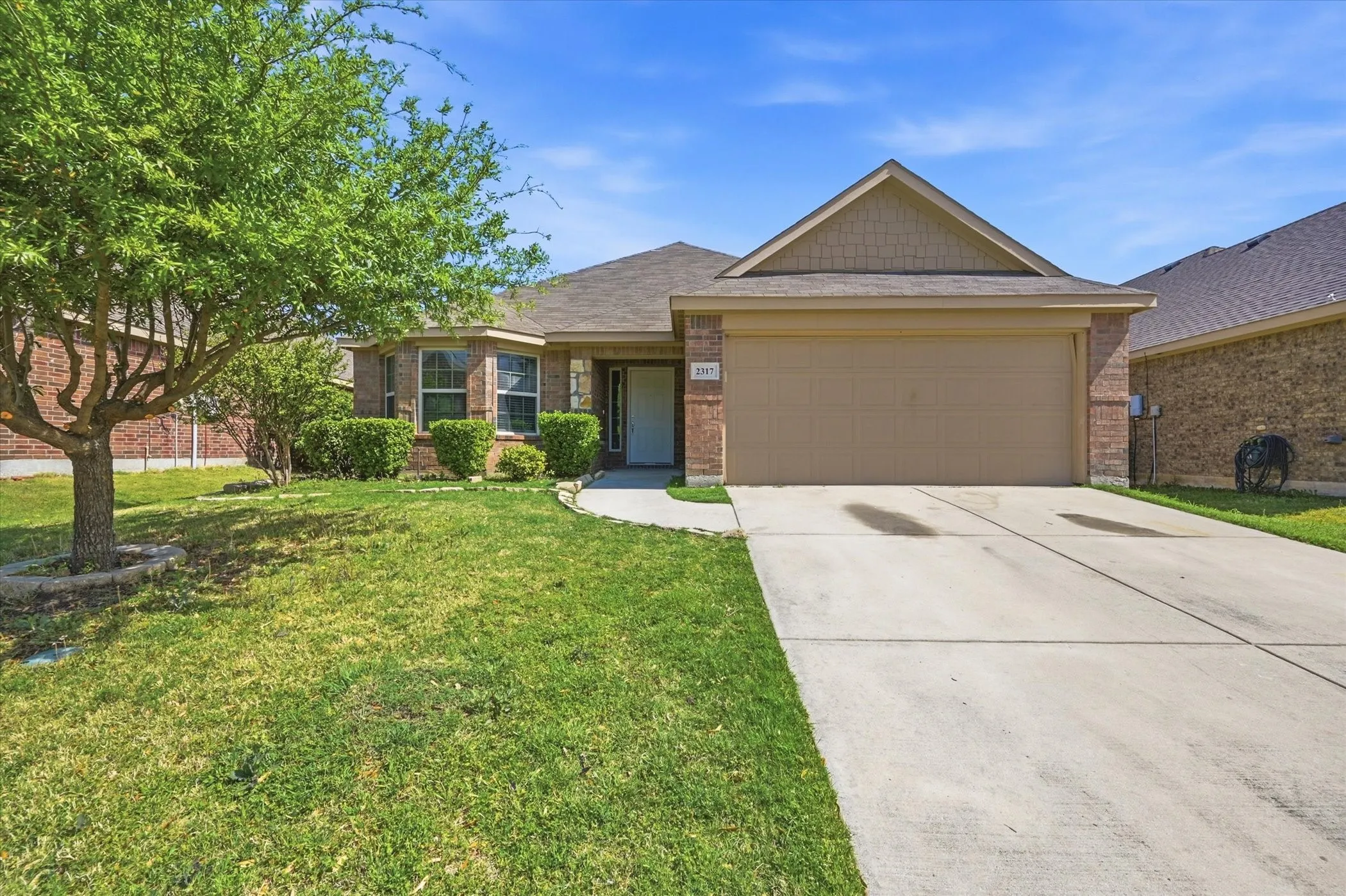 Single-story brick and siding residence featuring a two-car garage, a concrete driveway, and a front walkway