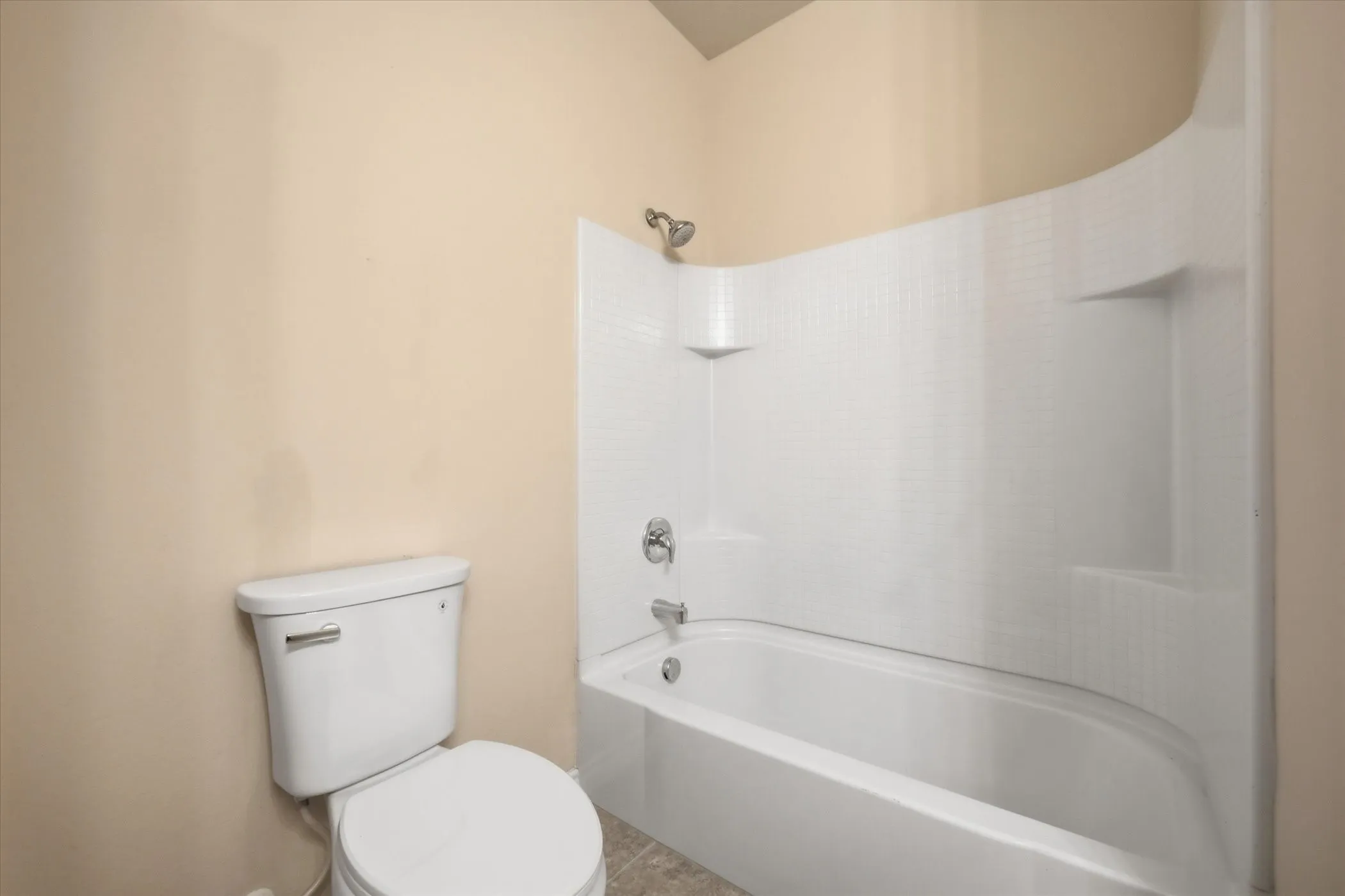 White porcelain bathtub and shower combination with an integrated shelving niche and a chrome showerhead