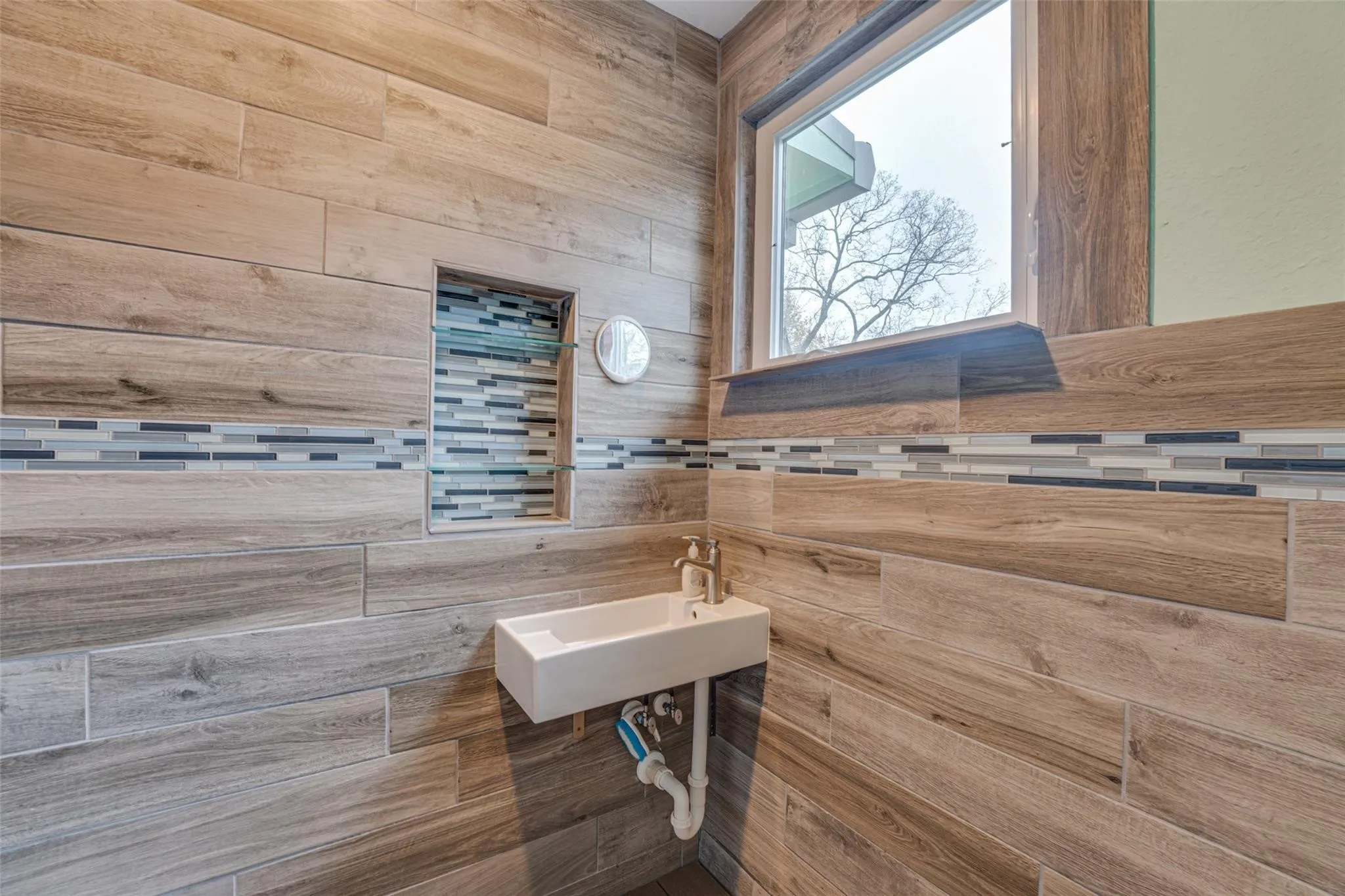 Wood-look tile walls featuring a decorative glass mosaic accent band