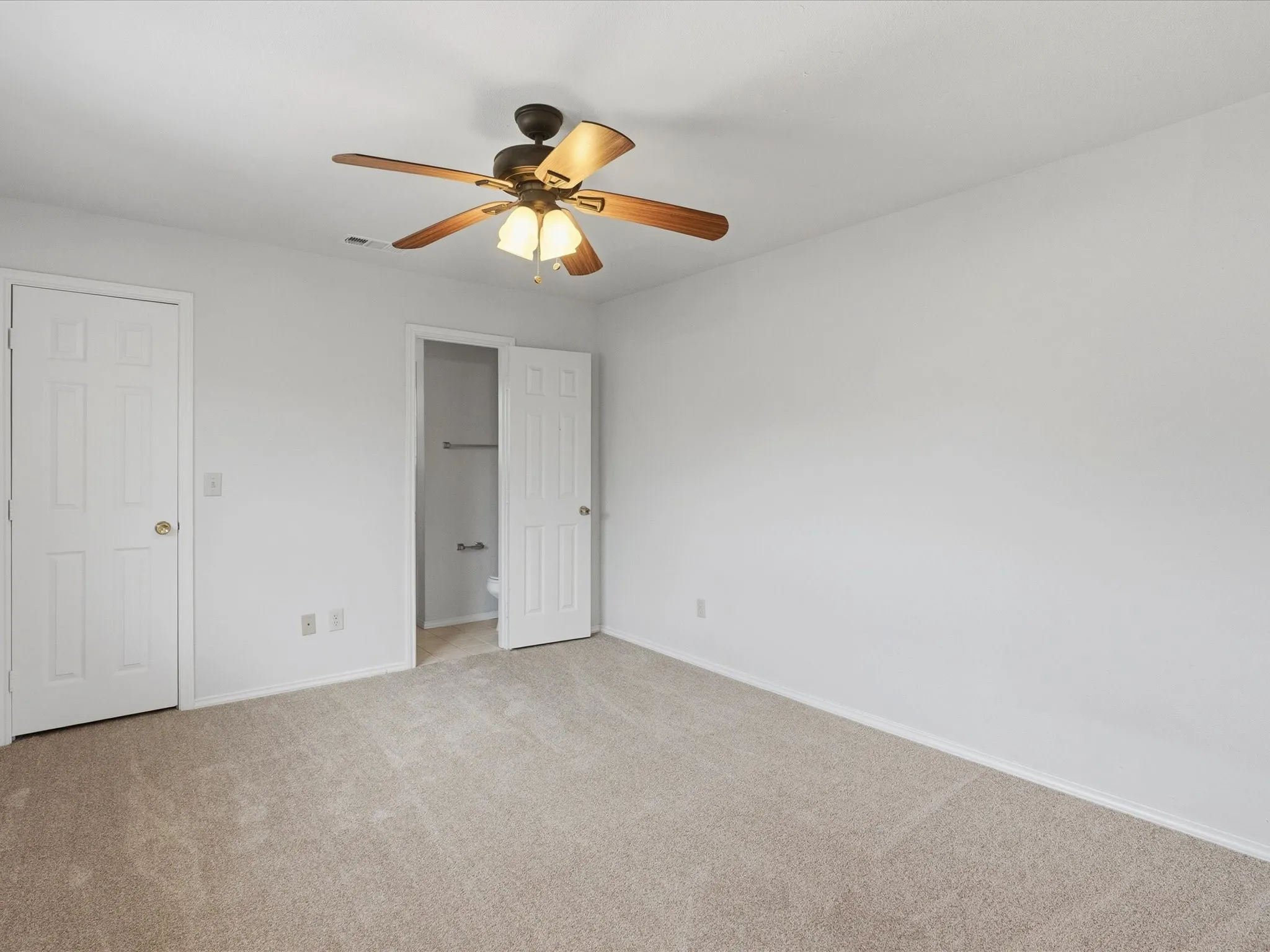 Carpeted room featuring a ceiling fan with light kit, white walls, and white trim