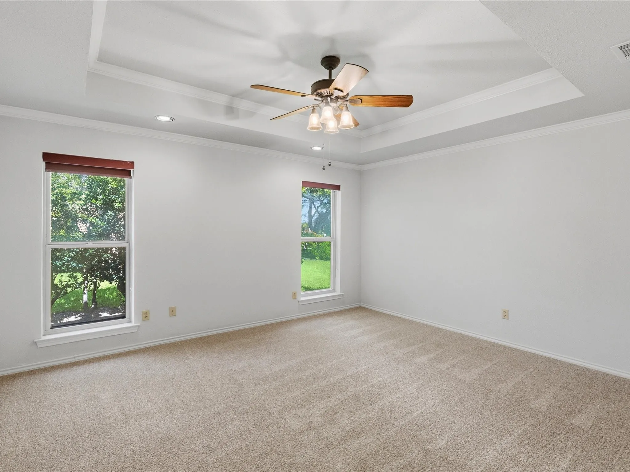 Spacious interior room featuring a tray ceiling, recessed lighting, and a ceiling fan