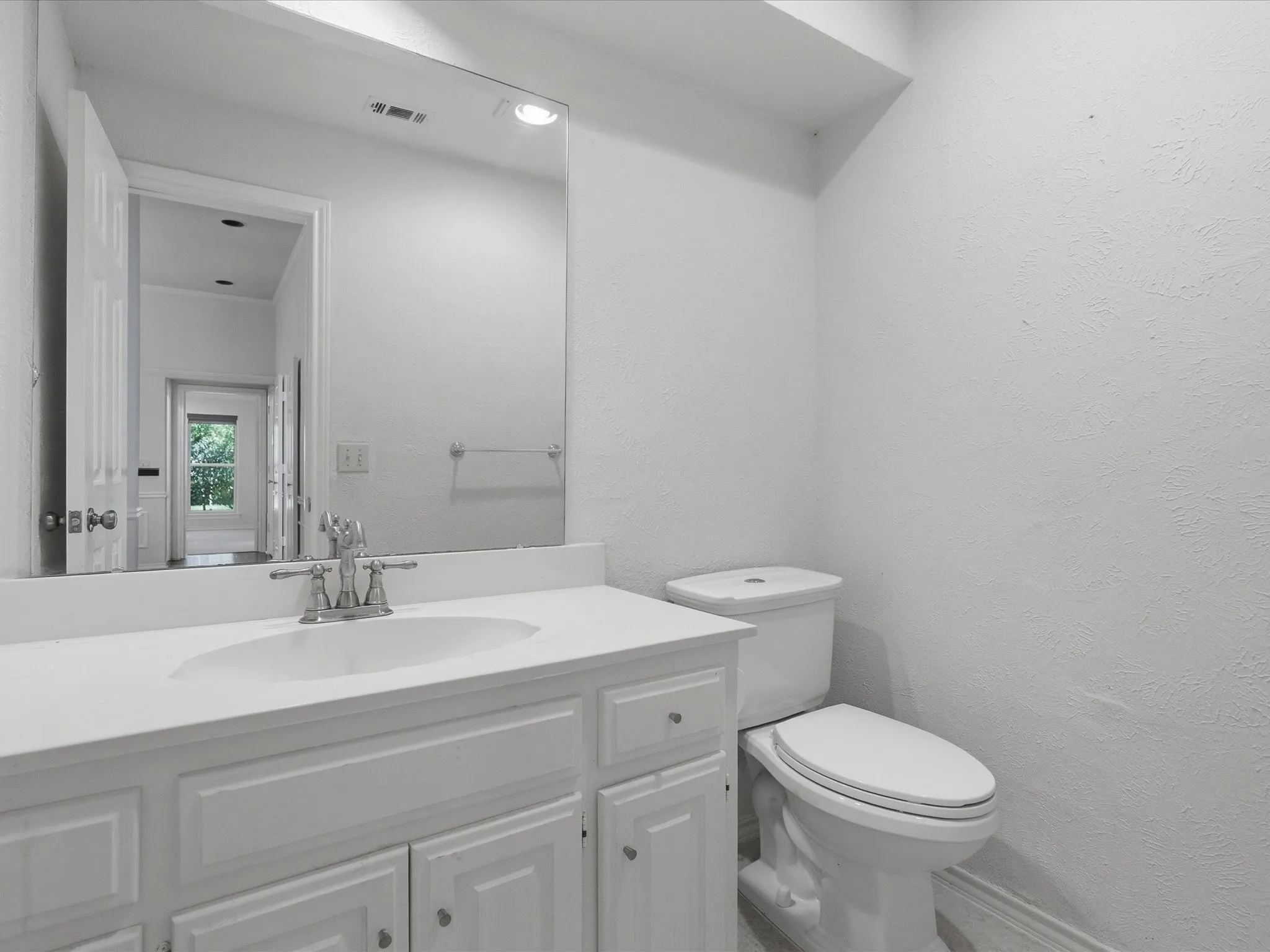 Bathroom vanity with an integrated sink, polished chrome faucet, and white paneled cabinetry