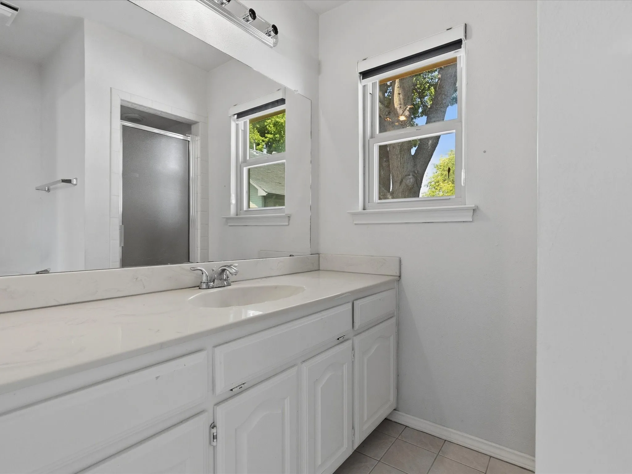 Bathroom vanity featuring a white countertop with an integrated sink and chrome faucet