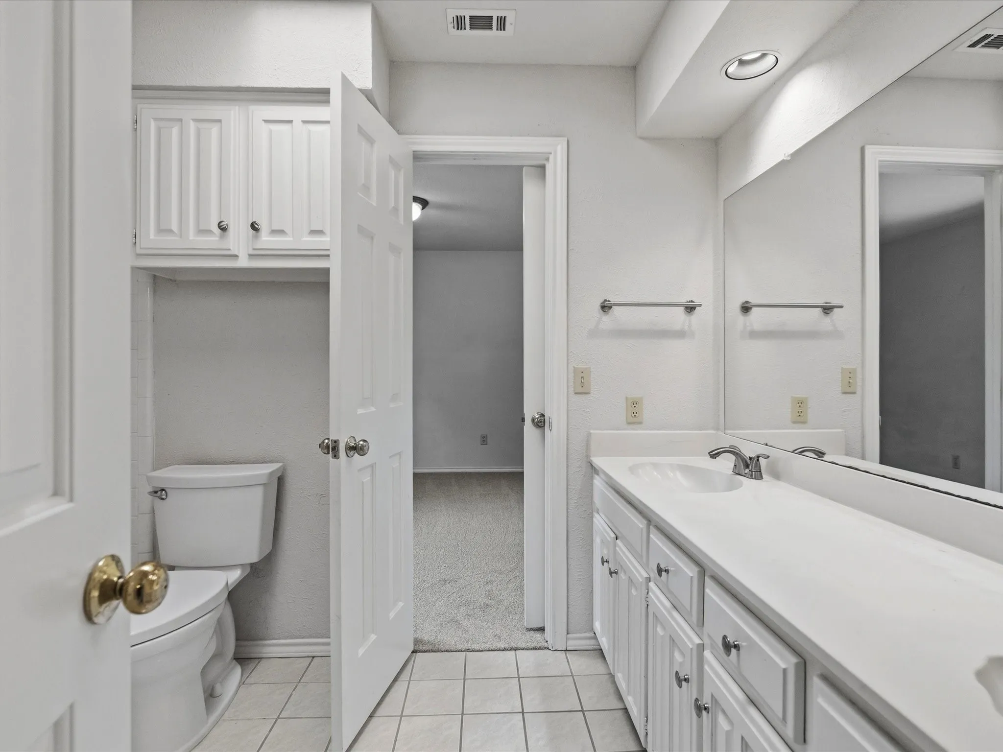 Bathroom featuring a white vanity with integrated sink, white cabinetry, and a large wall-mounted mirror