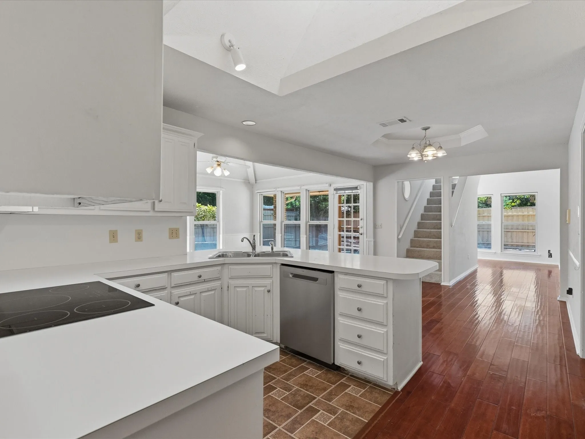 U-shaped kitchen featuring white cabinetry, light-toned countertops, and a built-in cooktop