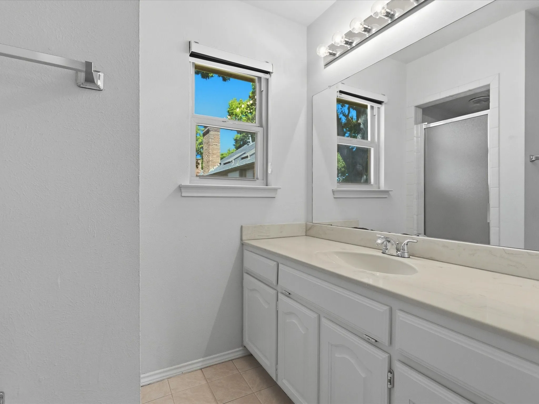 Bathroom vanity with an integrated sink, polished chrome faucet, and expansive mirror