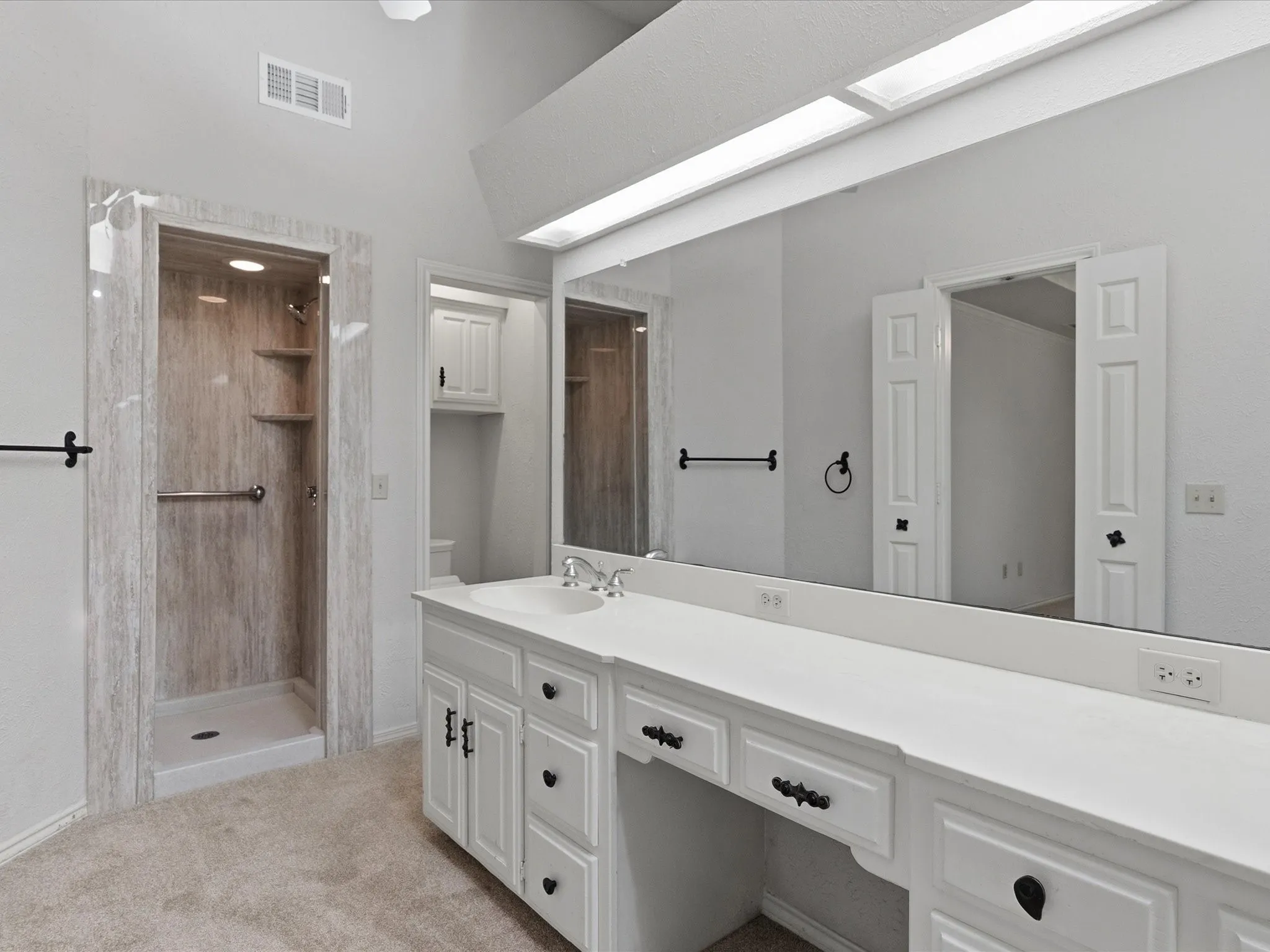 Vanity area featuring an integrated sink, expansive countertop, and white cabinetry with dark hardware