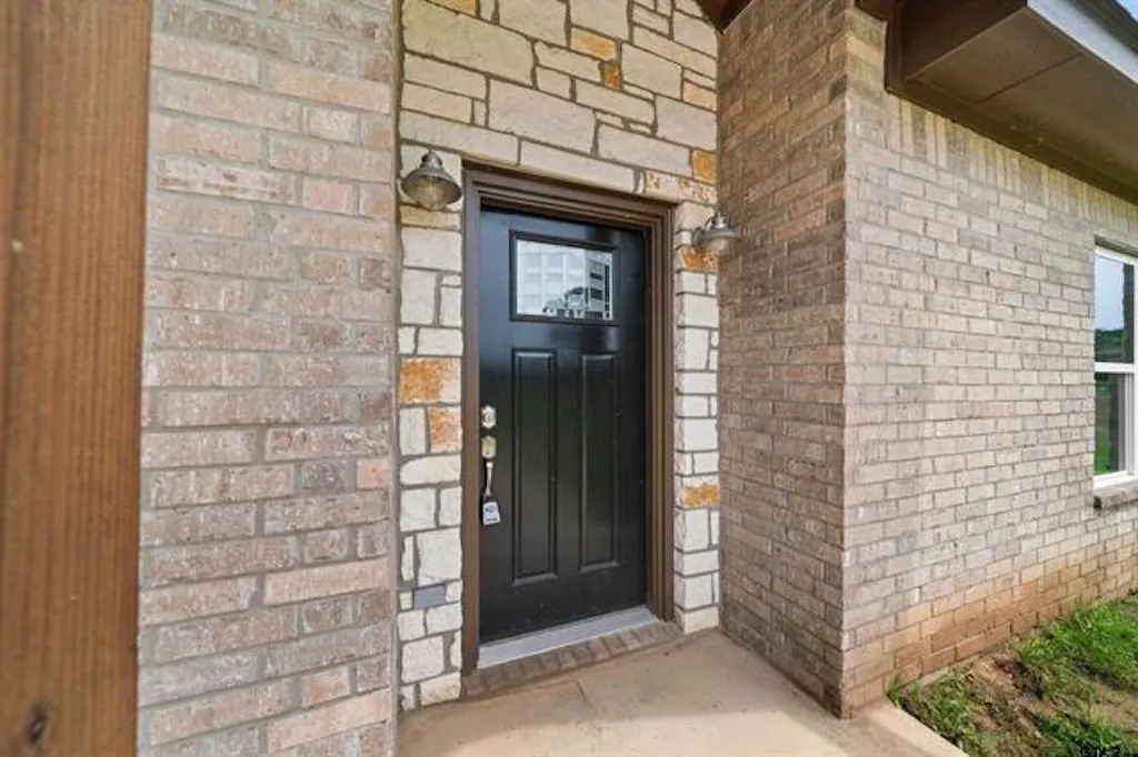 Entryway featuring a dark paneled door with glass insert, framed by stone and brick masonry
